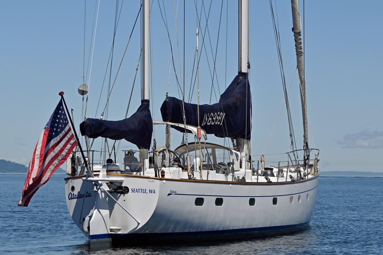 Sailing yacht "Atalanta," Abeking & Rasmussen Tripp 74, 1968, on calm waters with American flag.