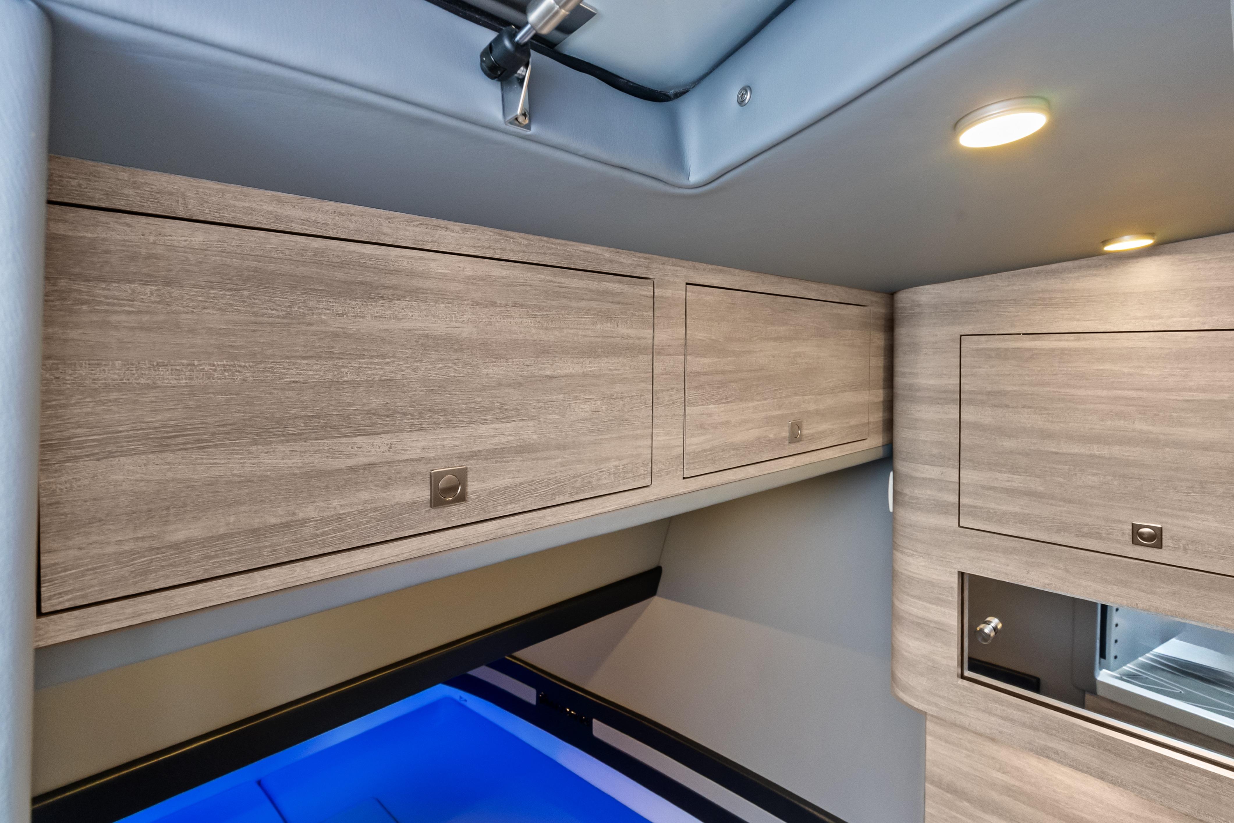 2027 Mystic Powerboats M4200 interior cabin with modern wood cabinetry and ambient lighting.