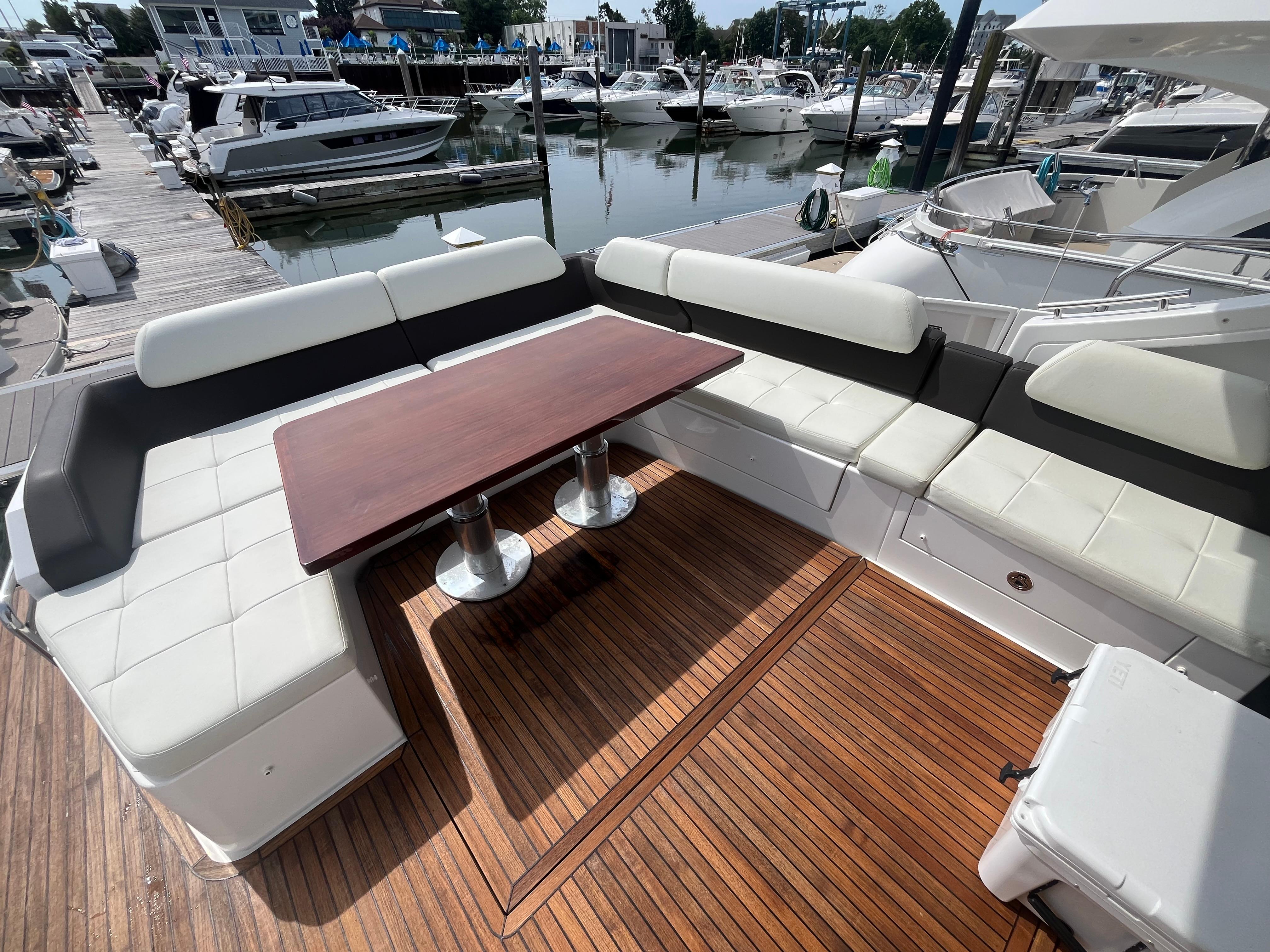 Luxurious 2014 Azimut 55S yacht deck with elegant seating and wooden table at marina.