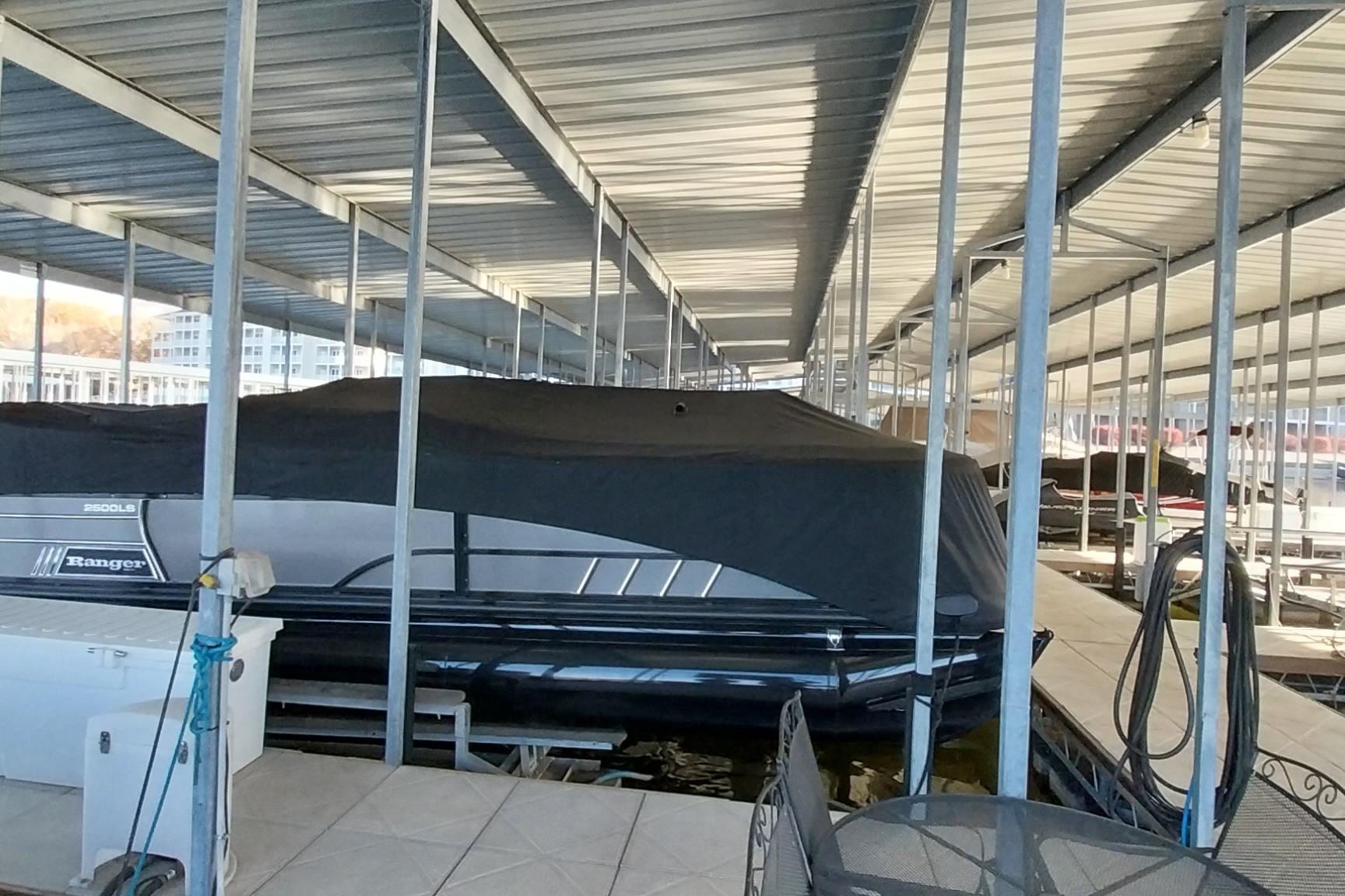 Covered 2023 Ranger 2500LS boat docked in a marina under a metal roof.