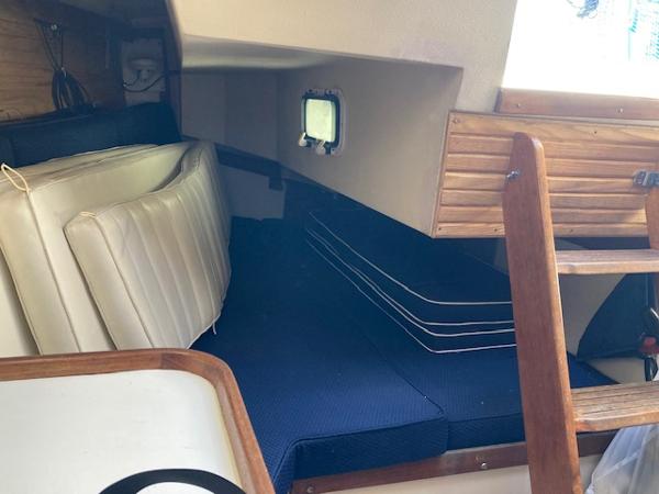 Interior cabin of a 1989 Catalina 30 sailboat with cushions and wooden ladder.