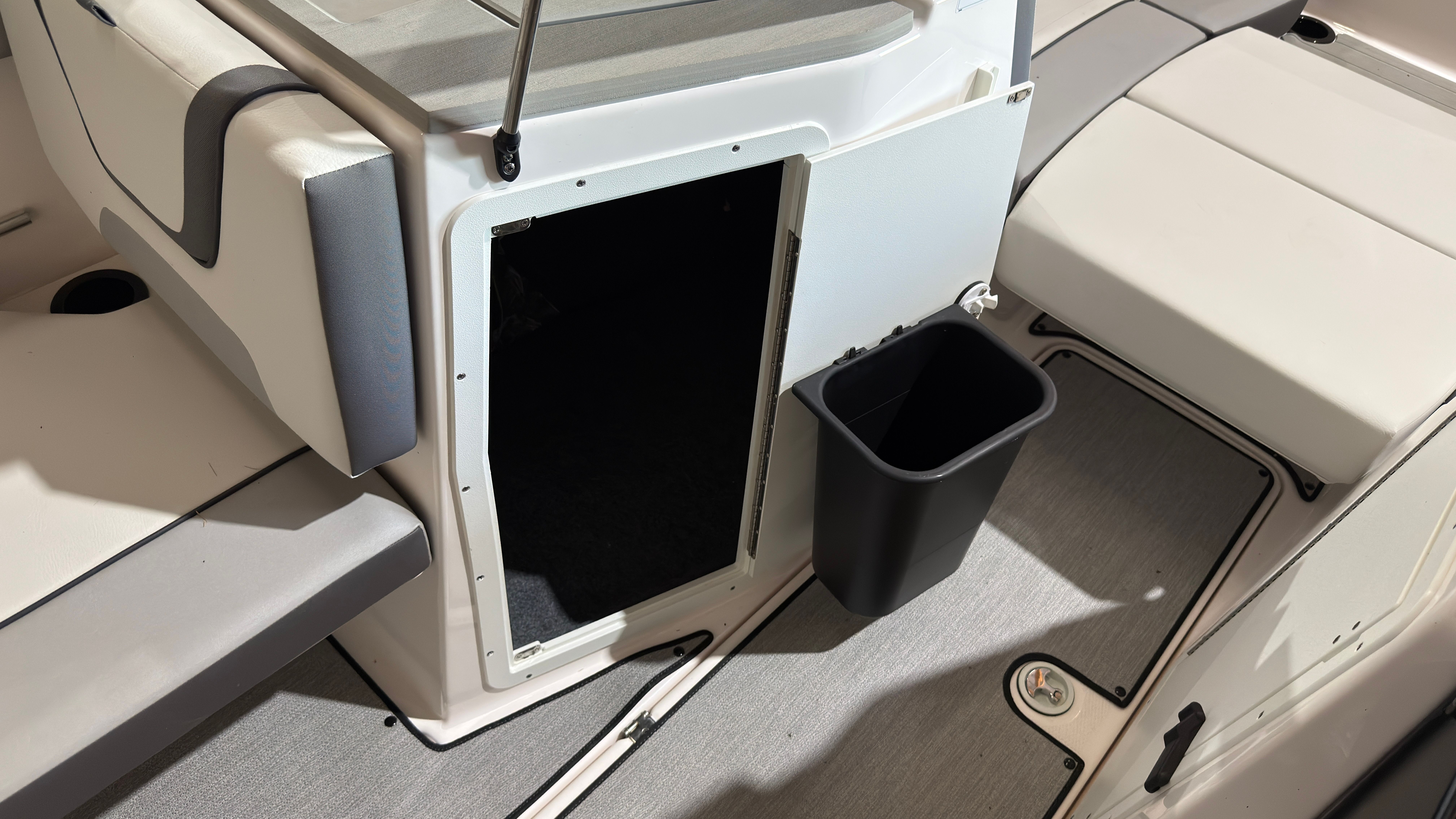 Interior of 2024 Yamaha Boats AR220 with storage compartment and trash bin.