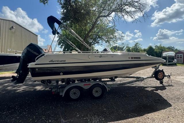 1999 Hurricane SunDeck Sport 201 OB boat on trailer, parked outdoors under a clear sky.
