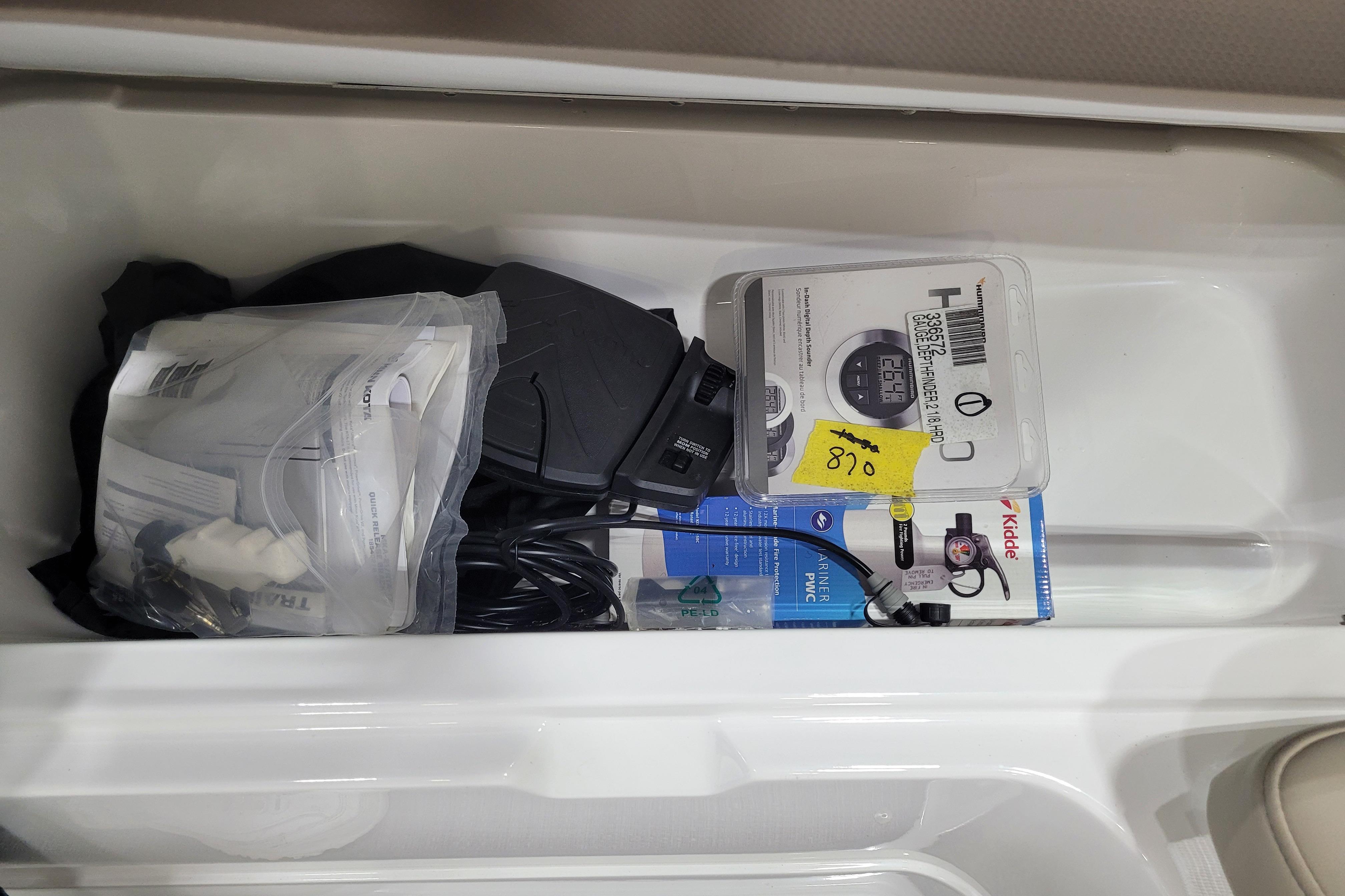 Storage compartment in a 2026 Tahoe 2150 boat with various accessories and manuals.