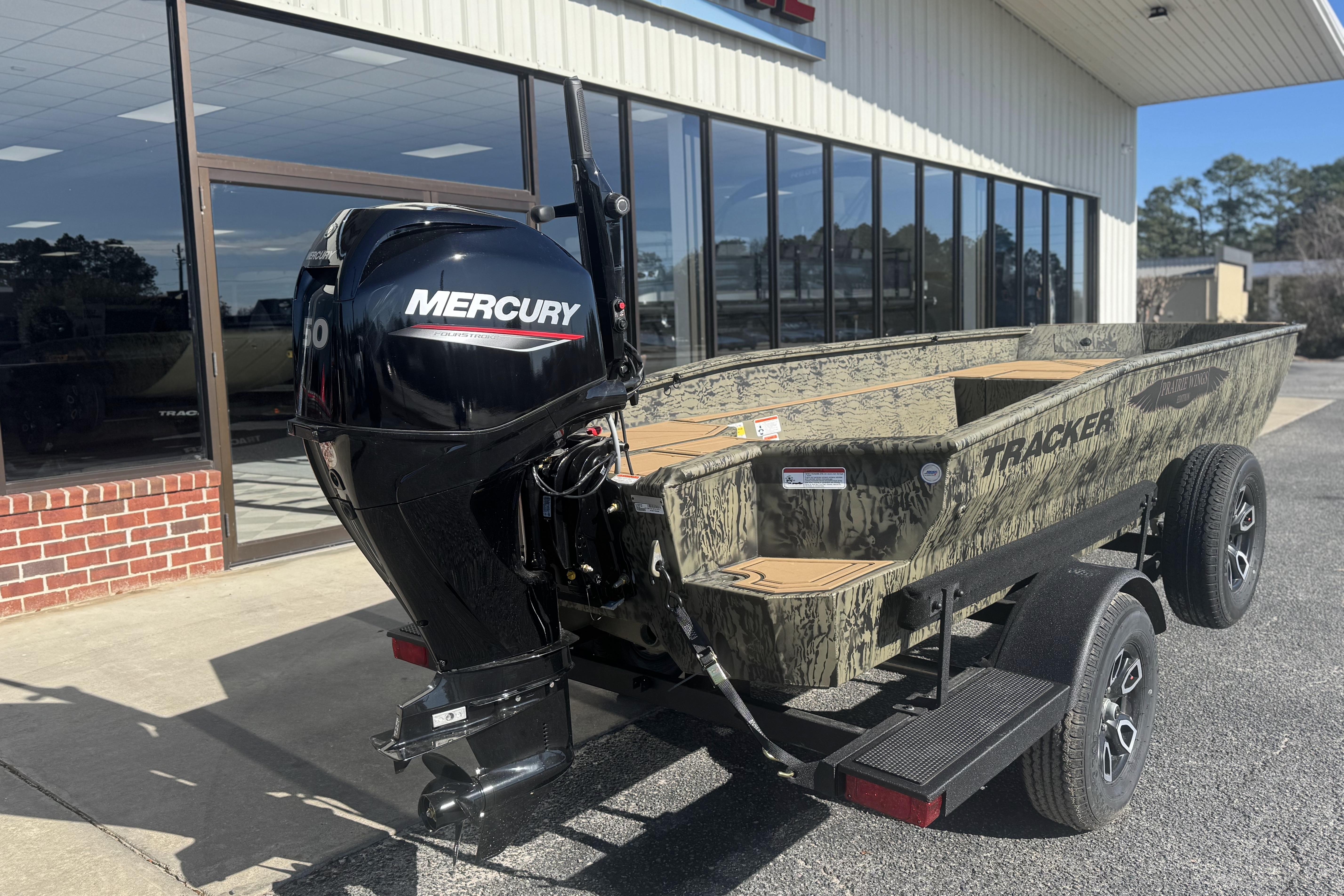 2026 Tracker Grizzly 1650 T Prairie Wings Edition boat with Mercury engine, parked outside dealership.