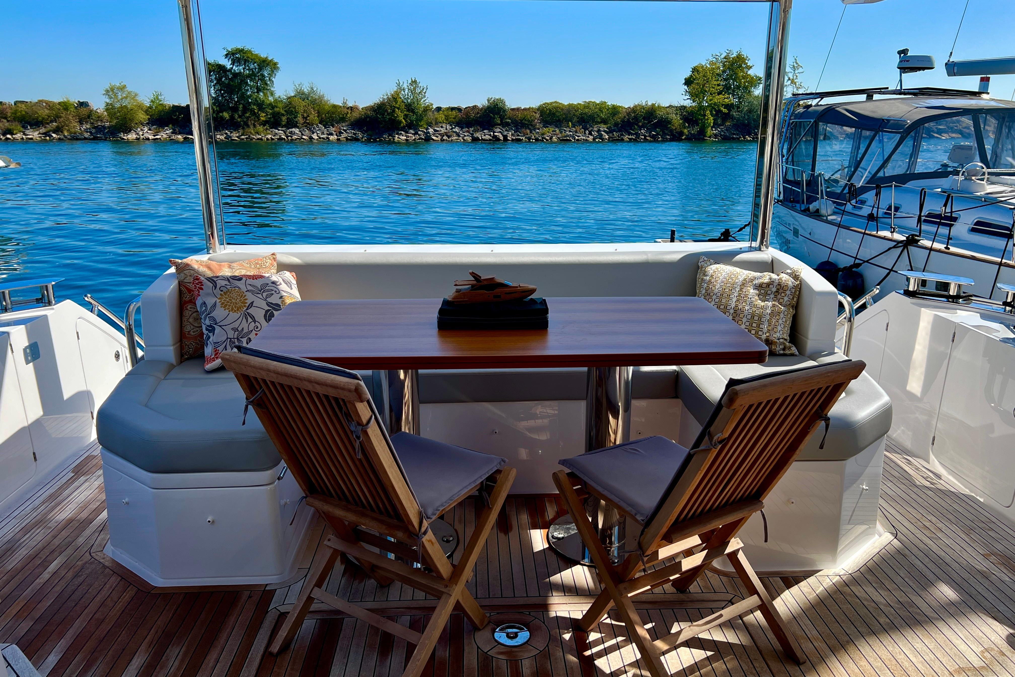 Luxurious 2024 Azimut Fly 60 yacht deck with seating, table, and scenic water view.
