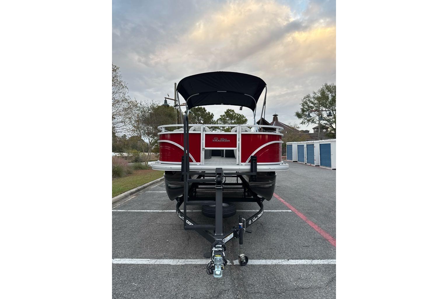 2026 Sun Tracker Fishin' Barge 22 DLX pontoon boat on trailer, parked outdoors.