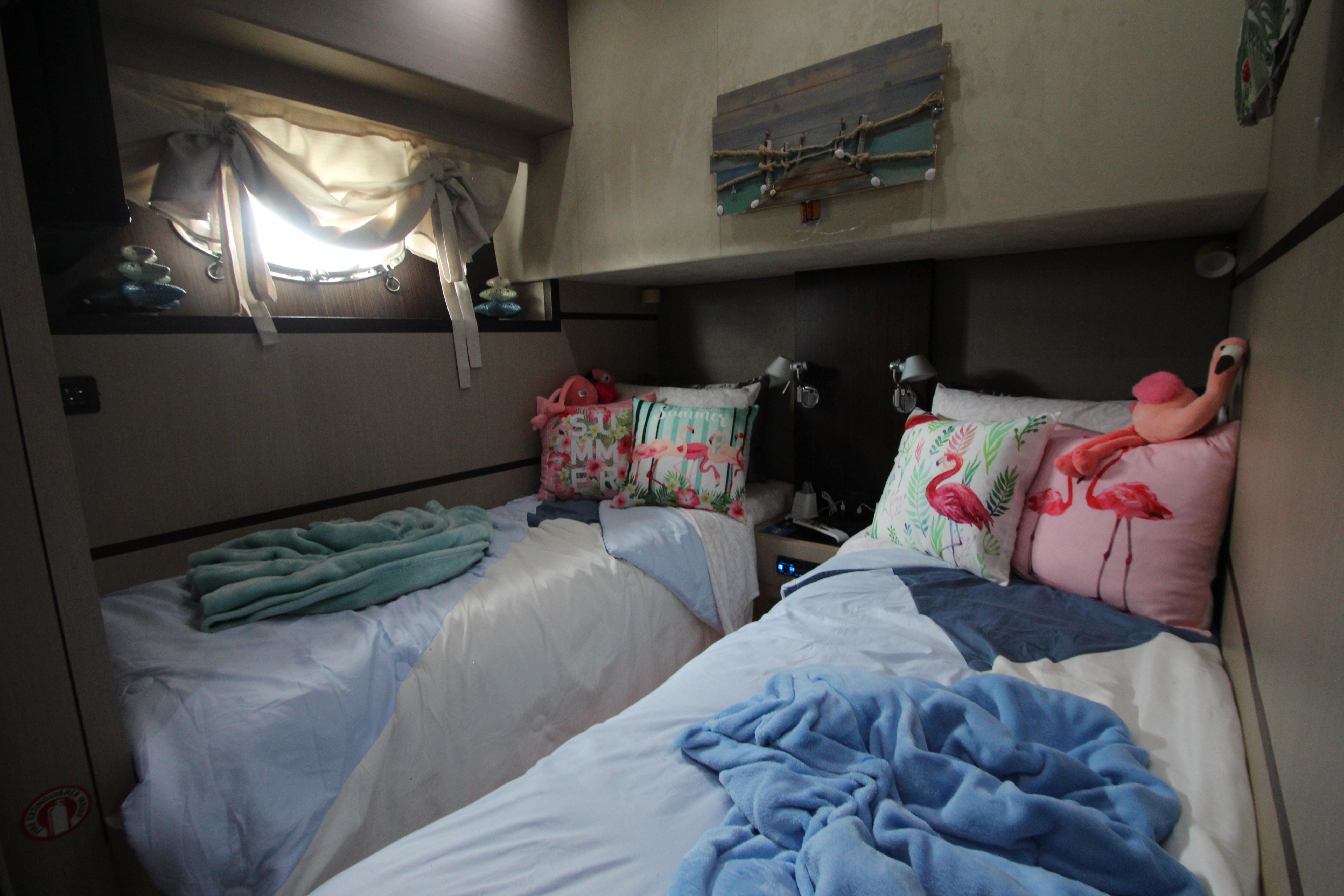 Cozy twin bedroom in 2007 Uniesse 70 Sport yacht with nautical decor.