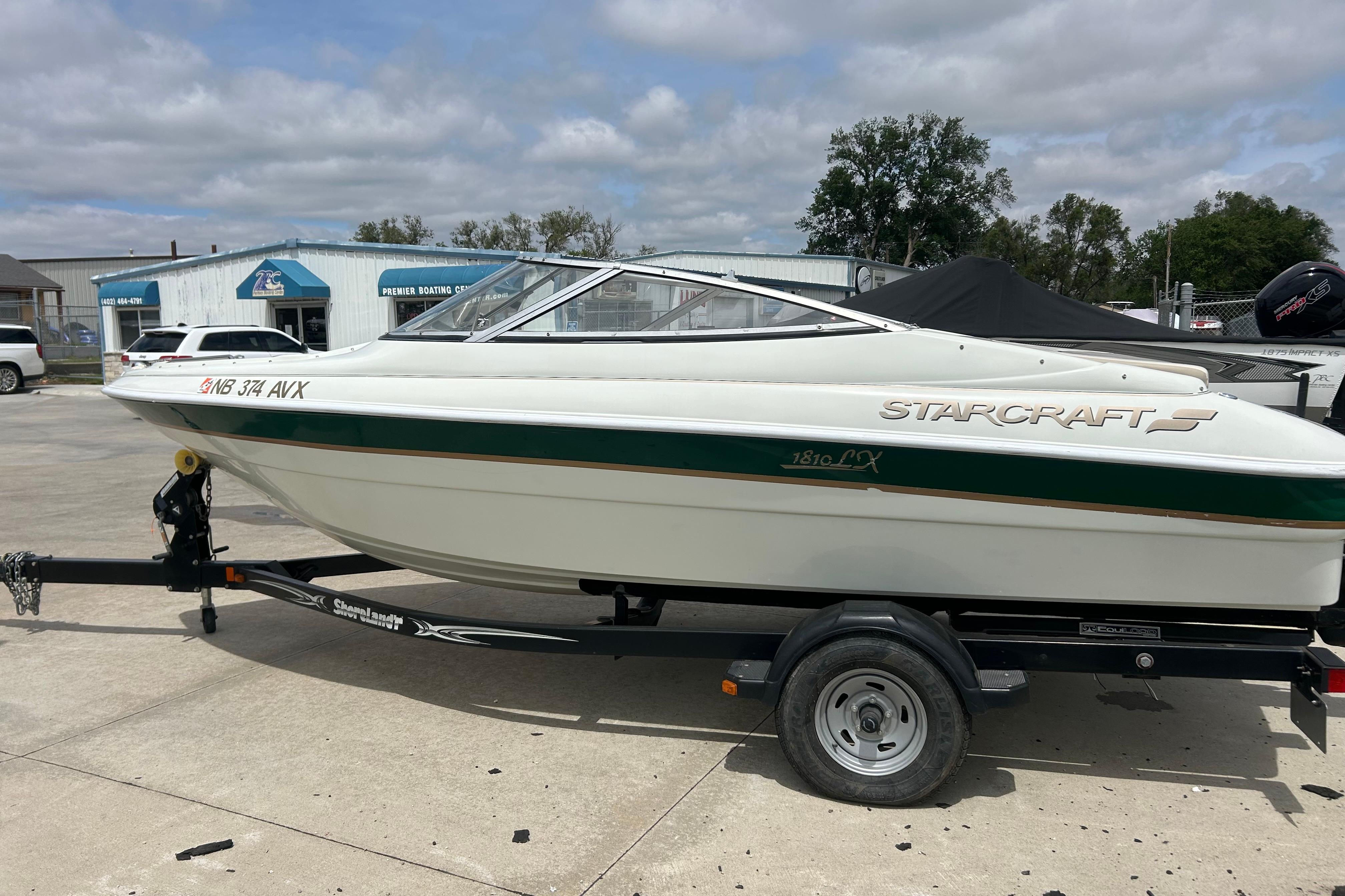 2000 Starcraft 1810 boat on trailer, parked outdoors under cloudy sky.