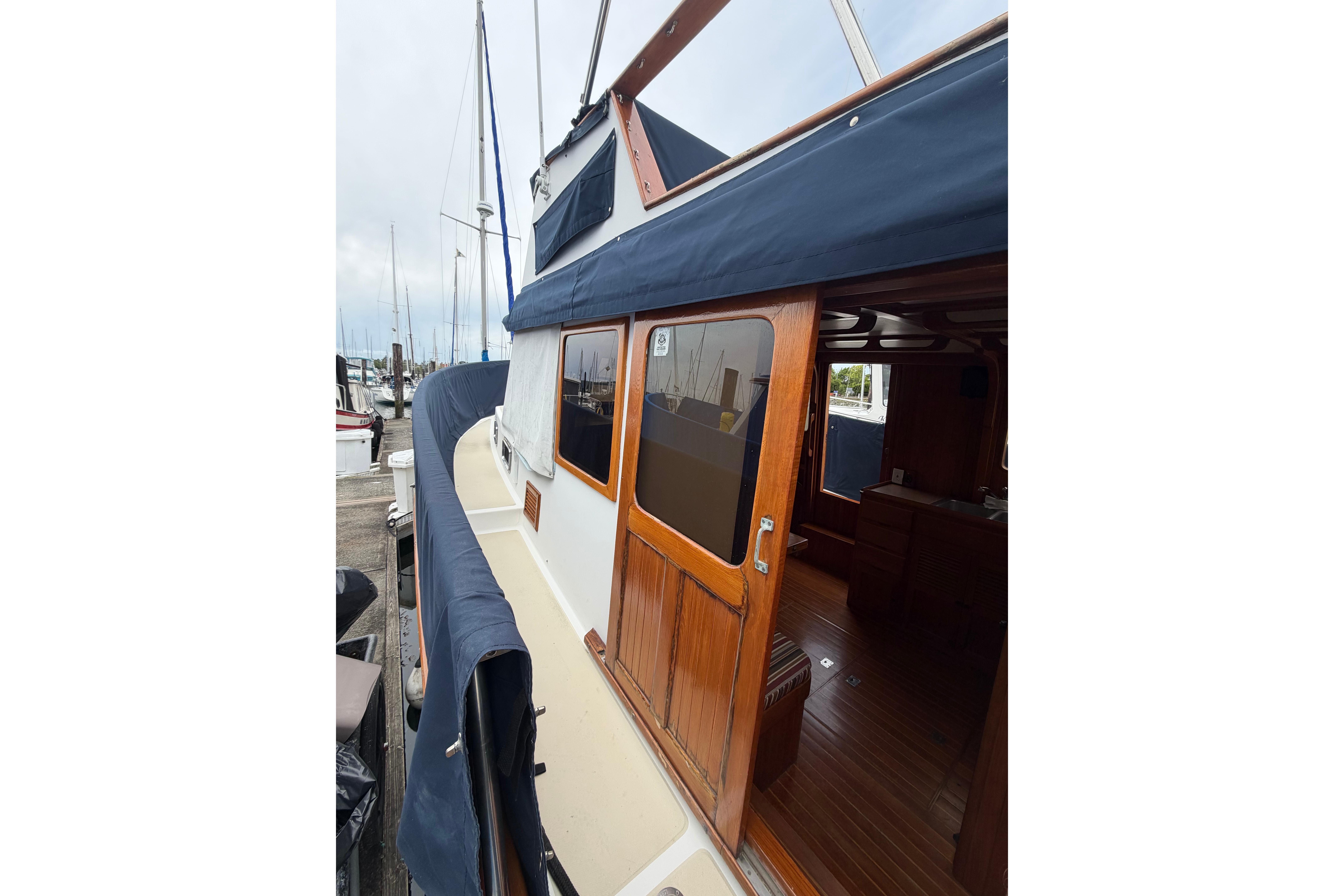 1988 Monk 36 boat with wooden cabin and blue canopy docked at marina.
