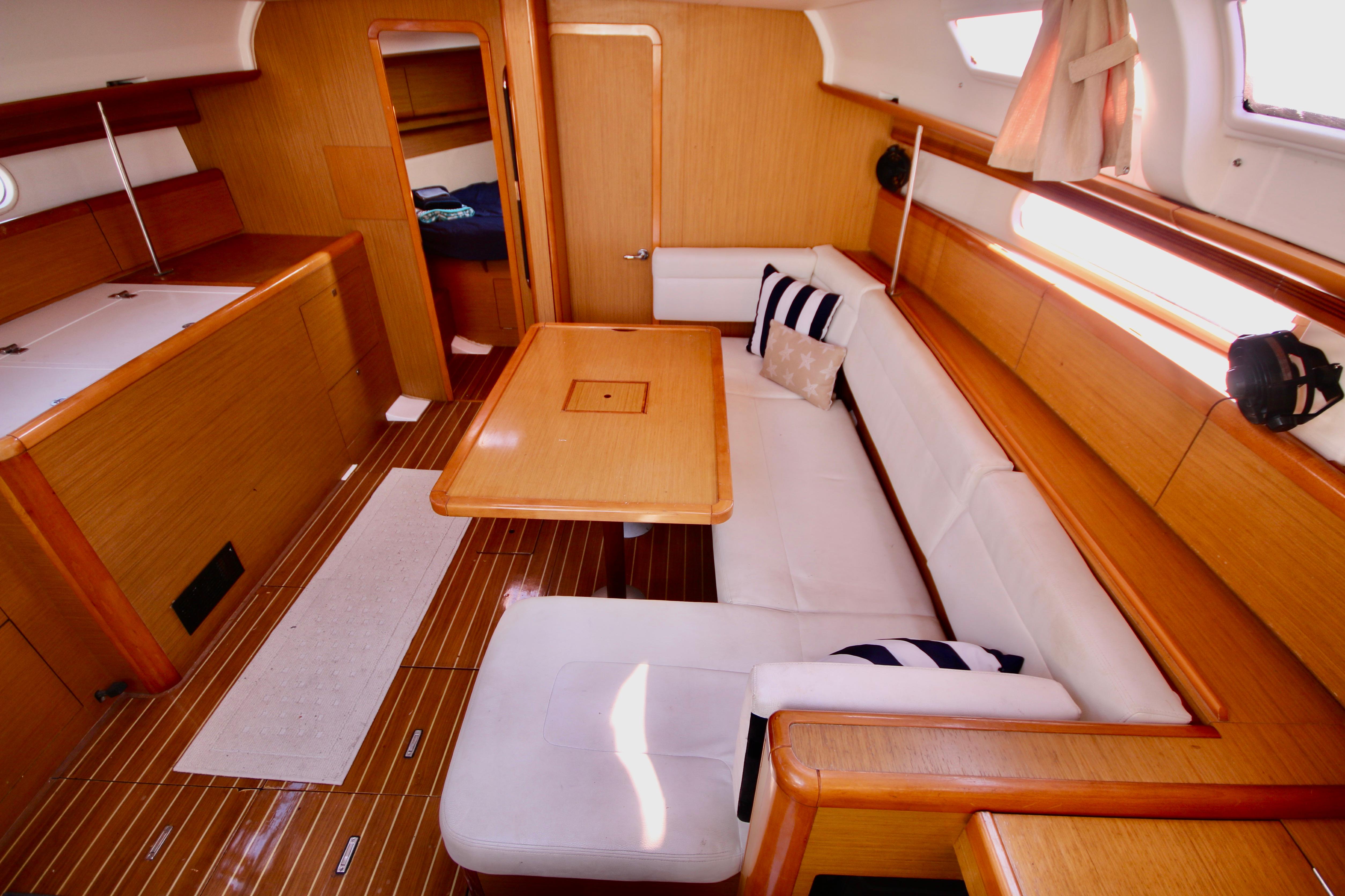Interior of 2009 Jeanneau Sun Odyssey 44i yacht with wooden finish and white seating.