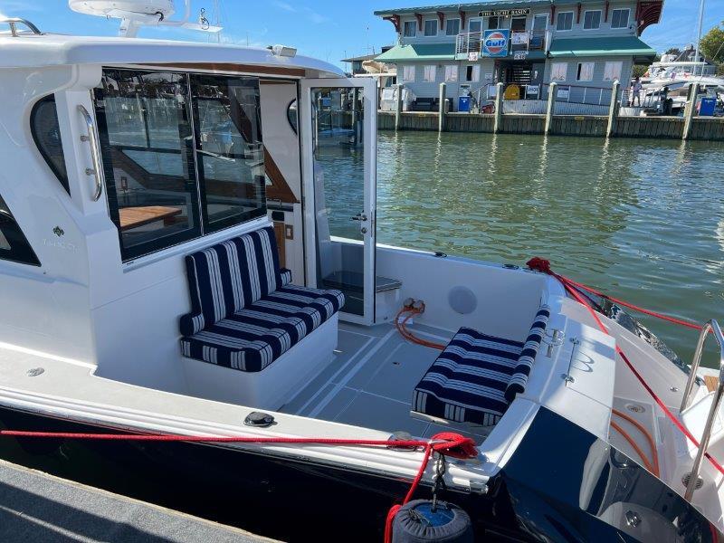 2024 True North 34 boat with striped seating, docked by a marina.