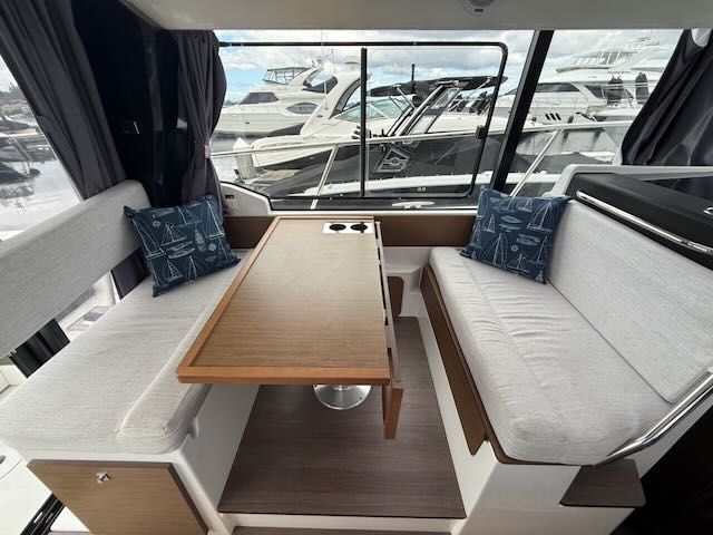 Interior of the Jeanneau NC 1095 featuring a sleek wooden table and comfortable bench seating.