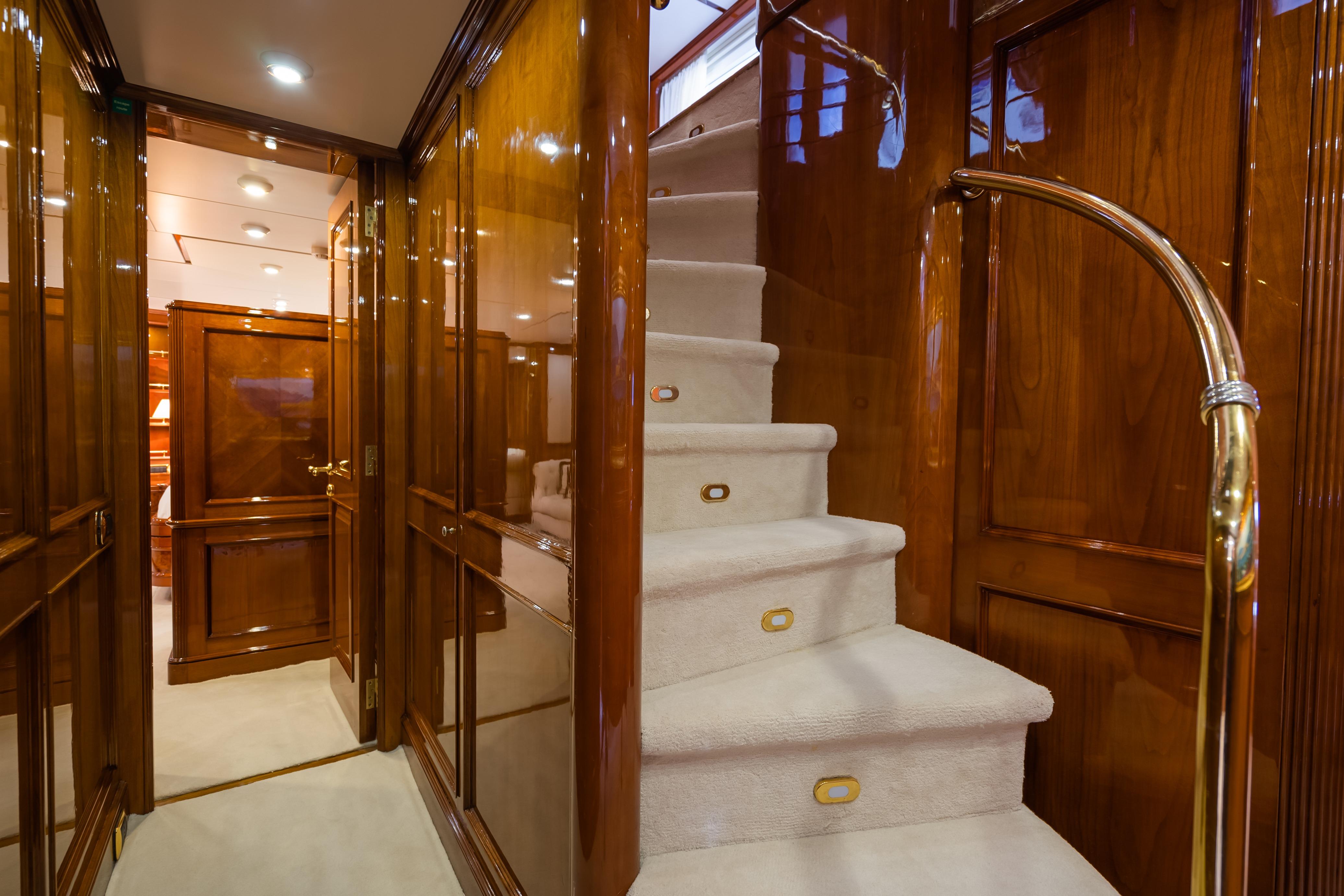 Luxurious interior of 1998 Benetti Classic yacht with polished wood and elegant staircase.