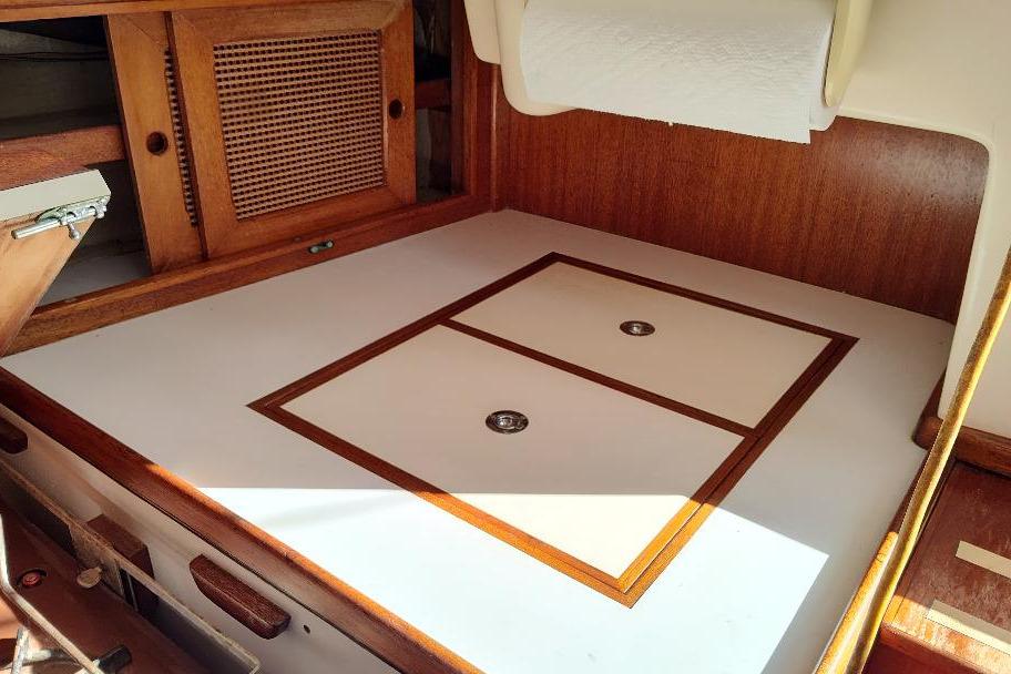 Interior of a 1979 Bristol Yawl sailboat, featuring wooden cabinetry and storage compartments.