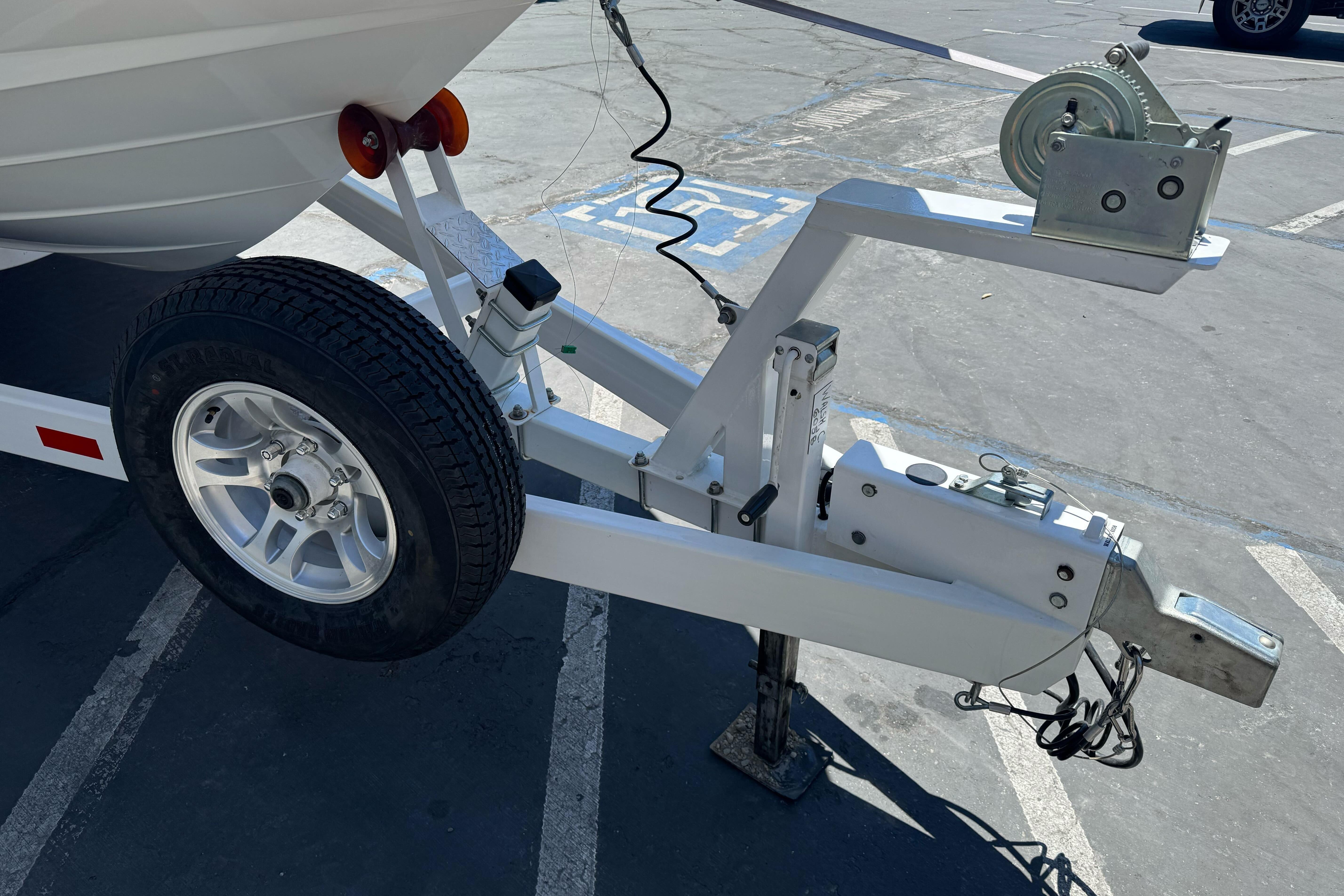Trailer hitch and wheel of a 2007 Sea Ray SLX 250 boat in a parking lot.
