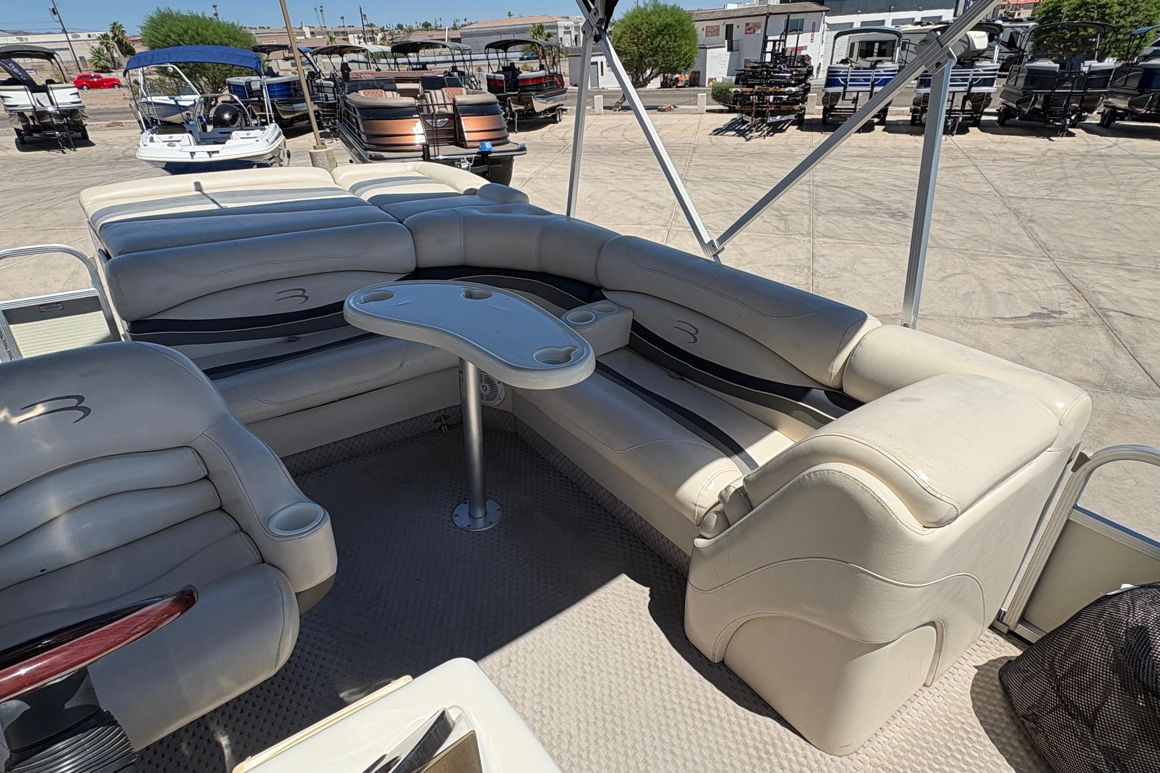 2005 Bennington 2575RFS I/O boat interior with beige seating and table, parked outdoors.