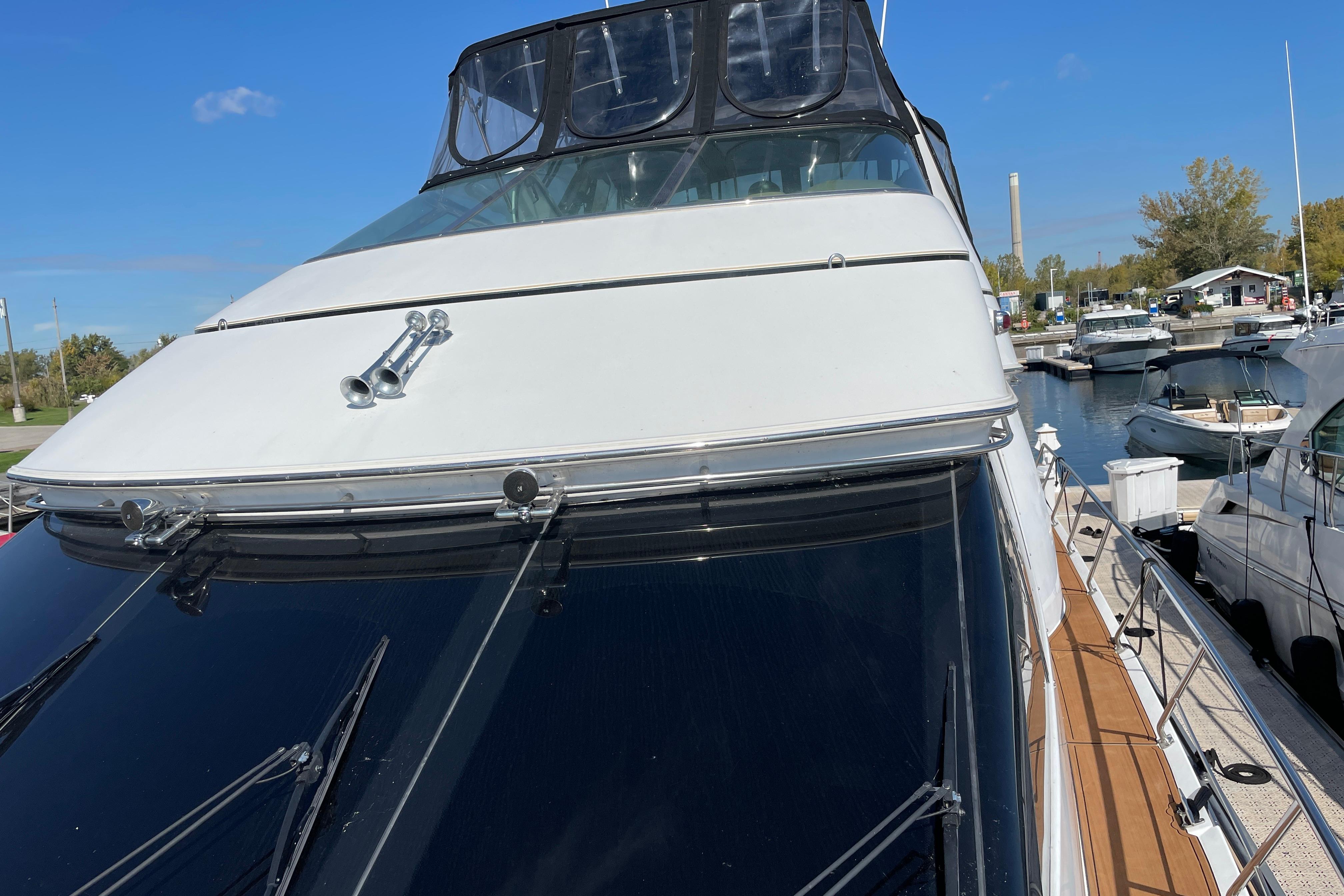 2002 Carver 570 Voyager Pilothouse yacht docked at marina under clear blue sky.
