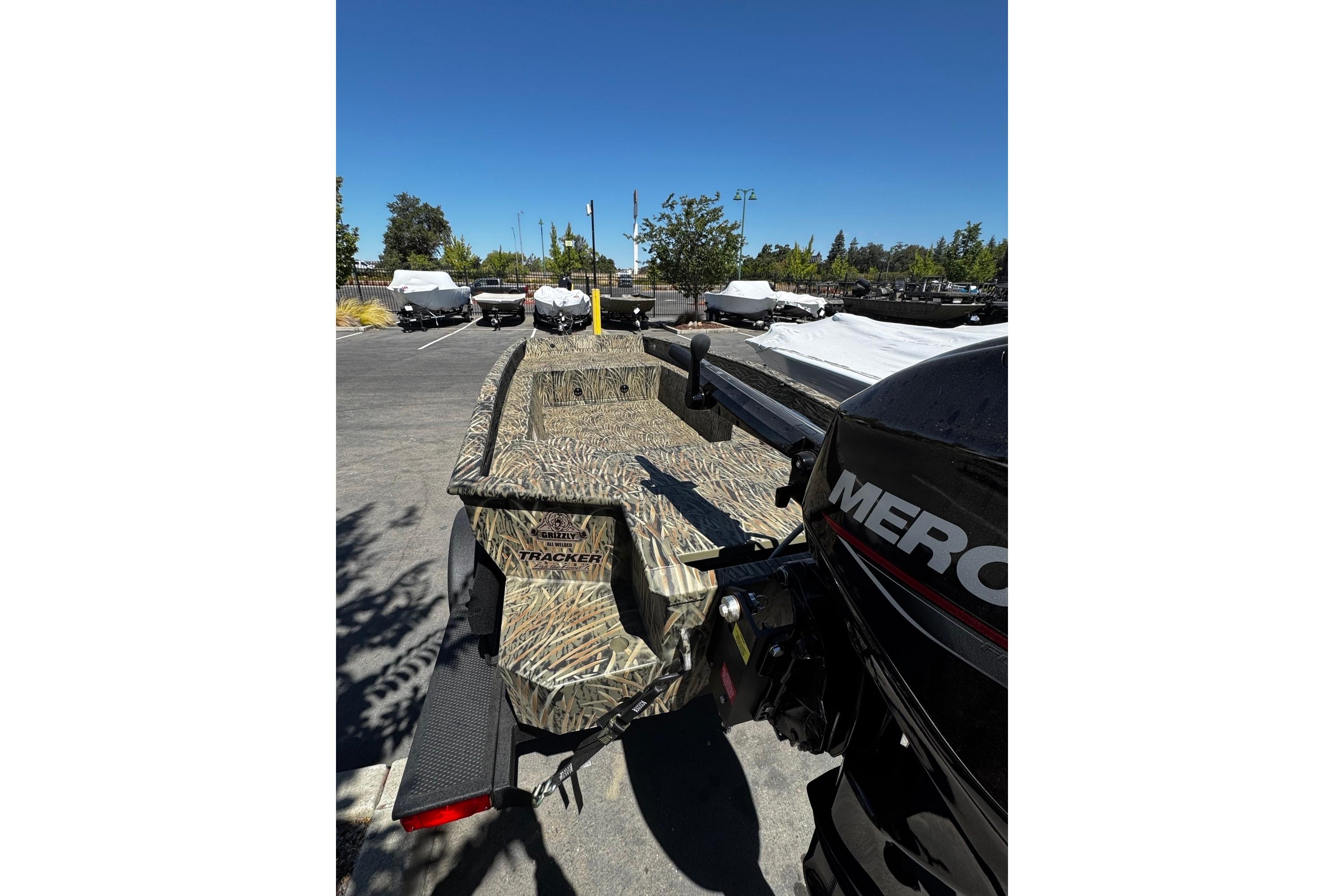 2026 Tracker Grizzly 1650 T Prairie Wings Edition boat with camouflage design in parking lot.