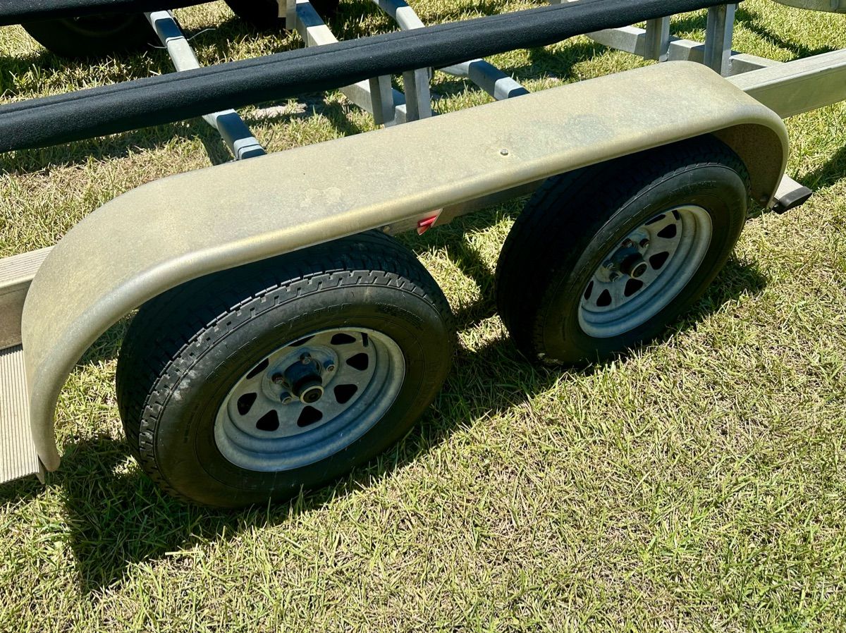 Boat trailer with two wheels on grass, part of a boat trailer.