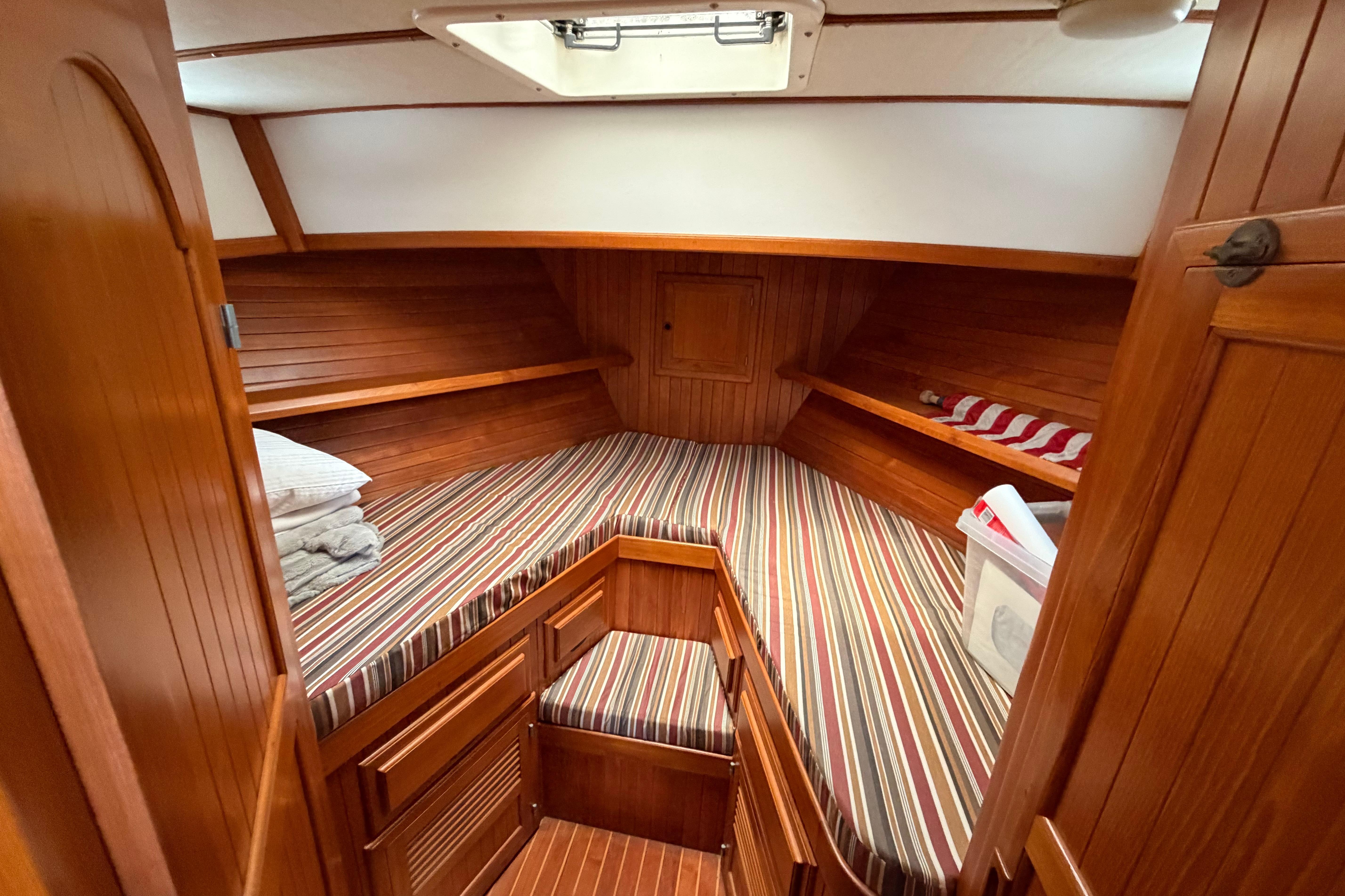 Cozy cabin interior of 1988 Monk 36 boat with striped bedding and wooden finish.