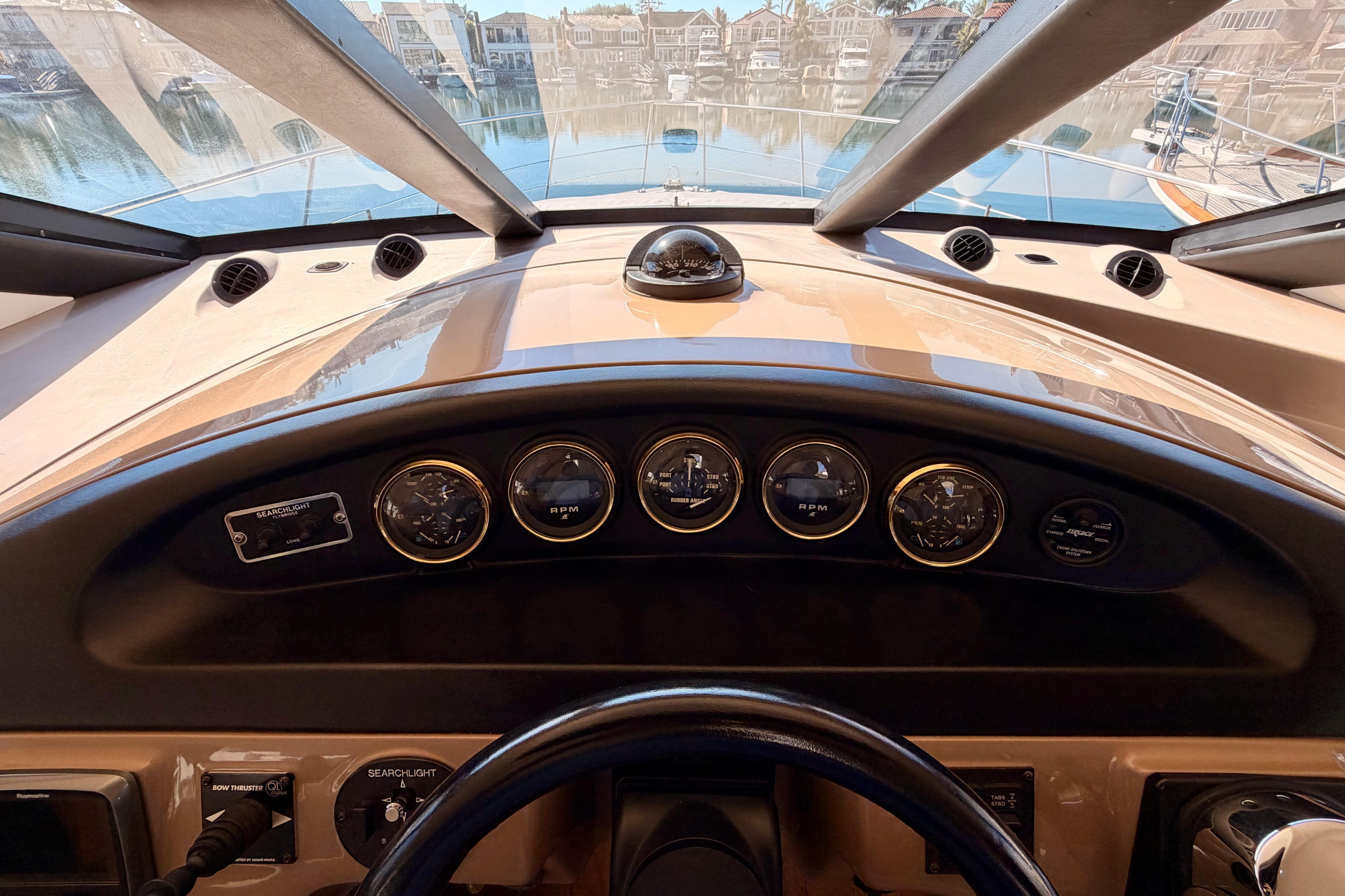 1999 Carver 530 Voyager Pilothouse dashboard with gauges and controls, overlooking marina.