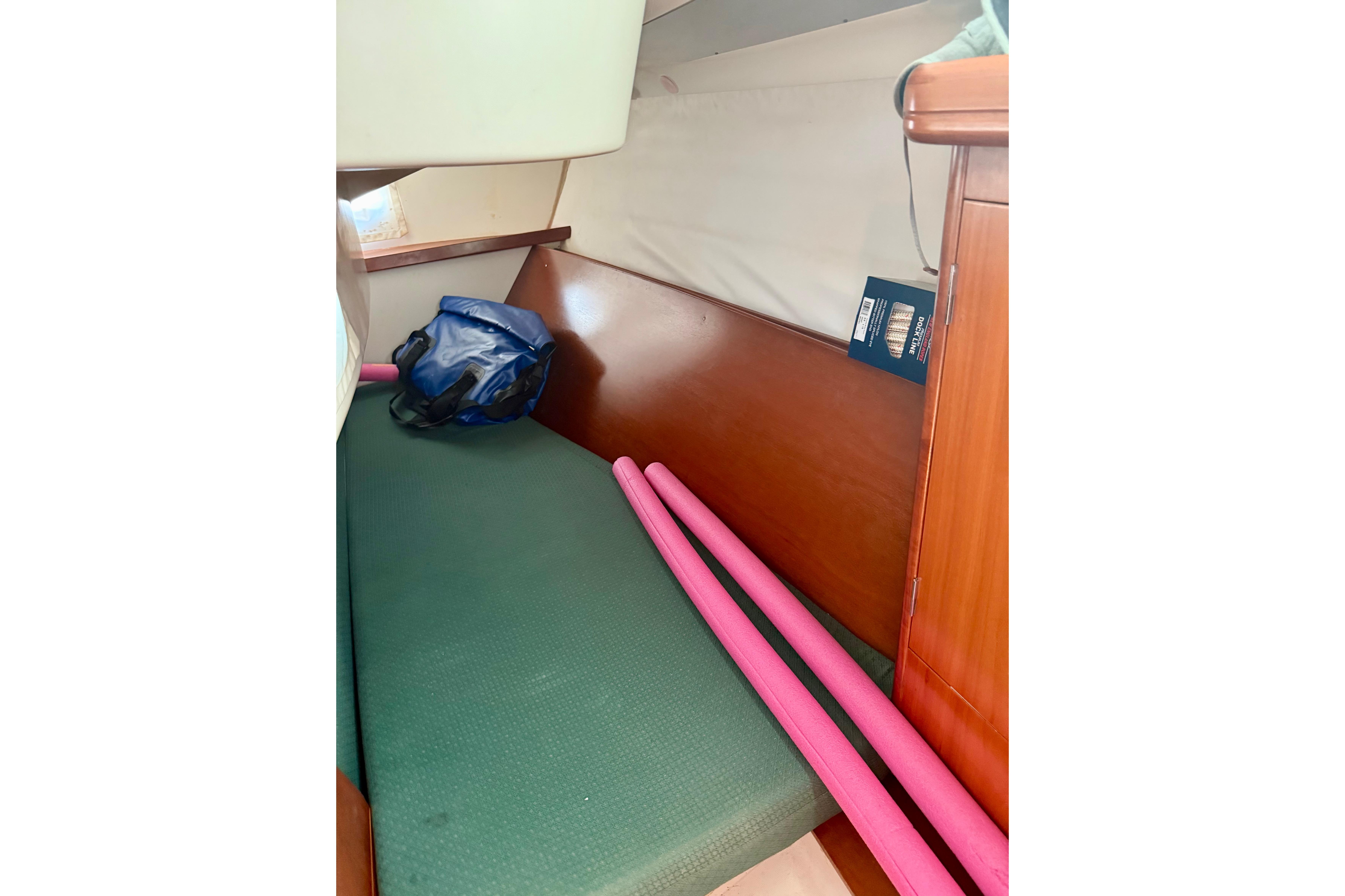 Interior cabin of 2002 Beneteau Oceanis Clipper 311 with green cushion and pink pool noodles.