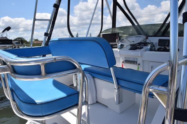 1976 Bertram Flybridge Cruiser with blue seating and steering console under a sunny sky.