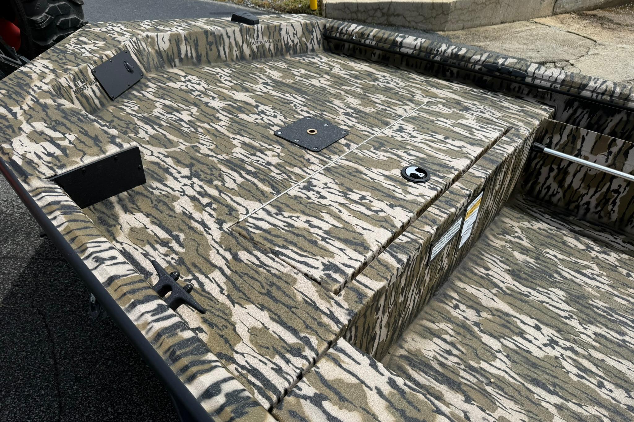 Camouflage-patterned deck of 2026 Avid 16 Commander boat, featuring storage compartments.