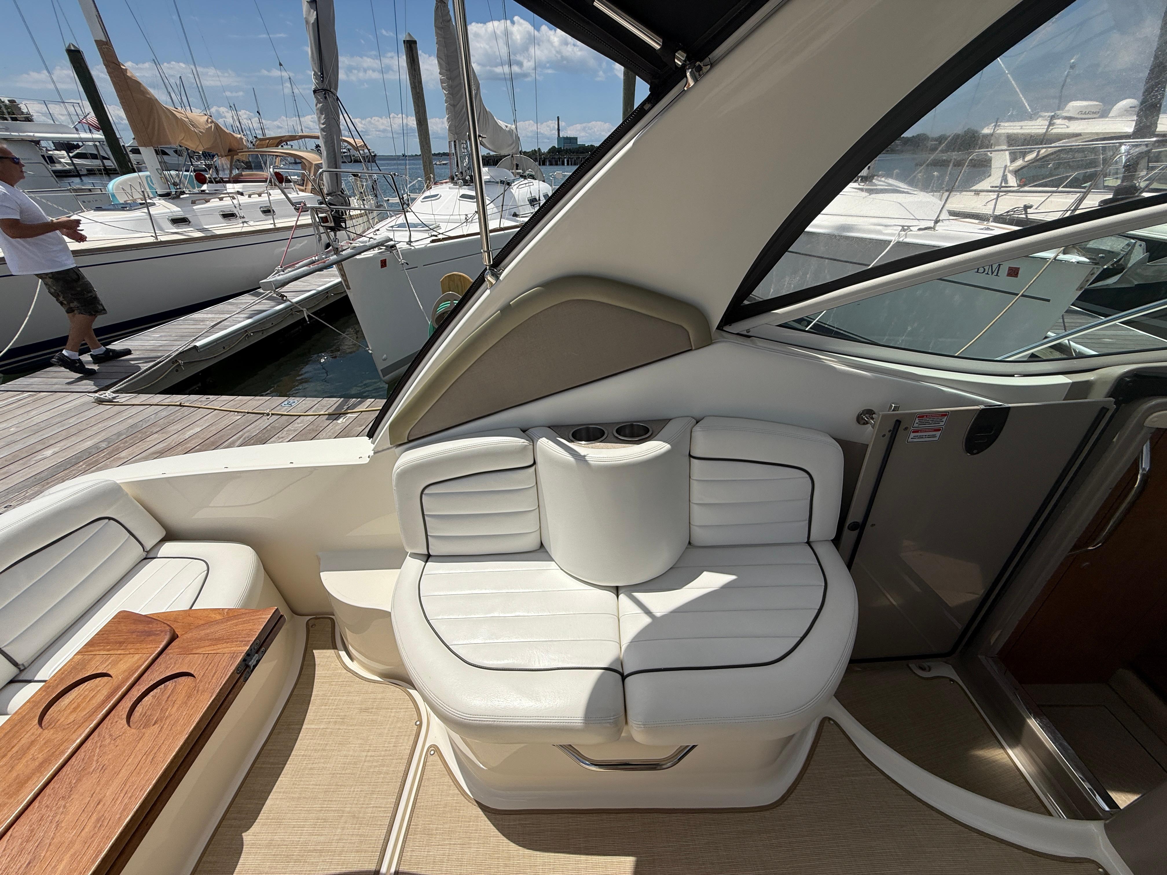 2006 Sea Ray 290 Sundancer interior with white seating and wooden table, docked at marina.