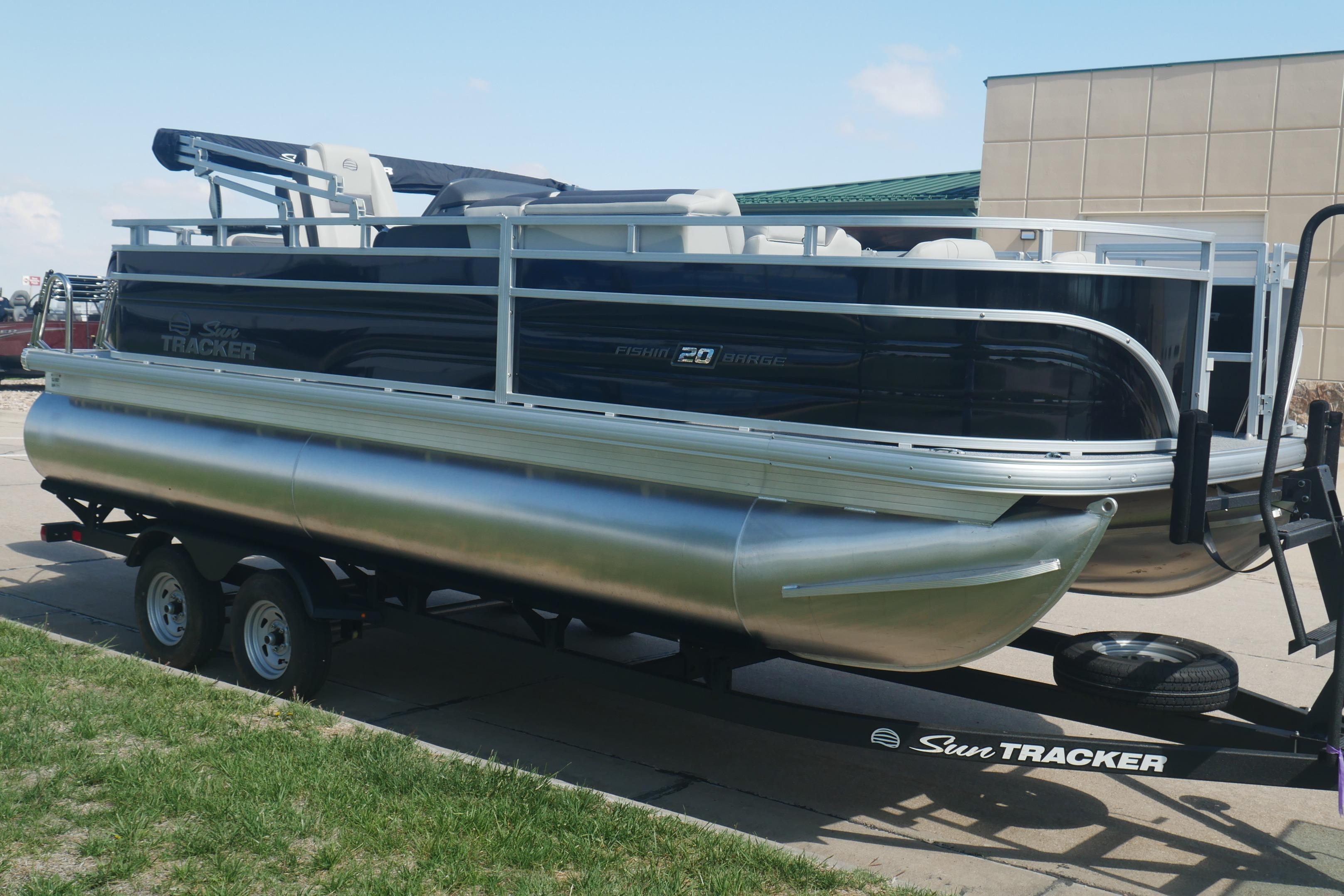 2026 Sun Tracker Fishin' Barge 20 DLX pontoon boat on trailer, parked outdoors.