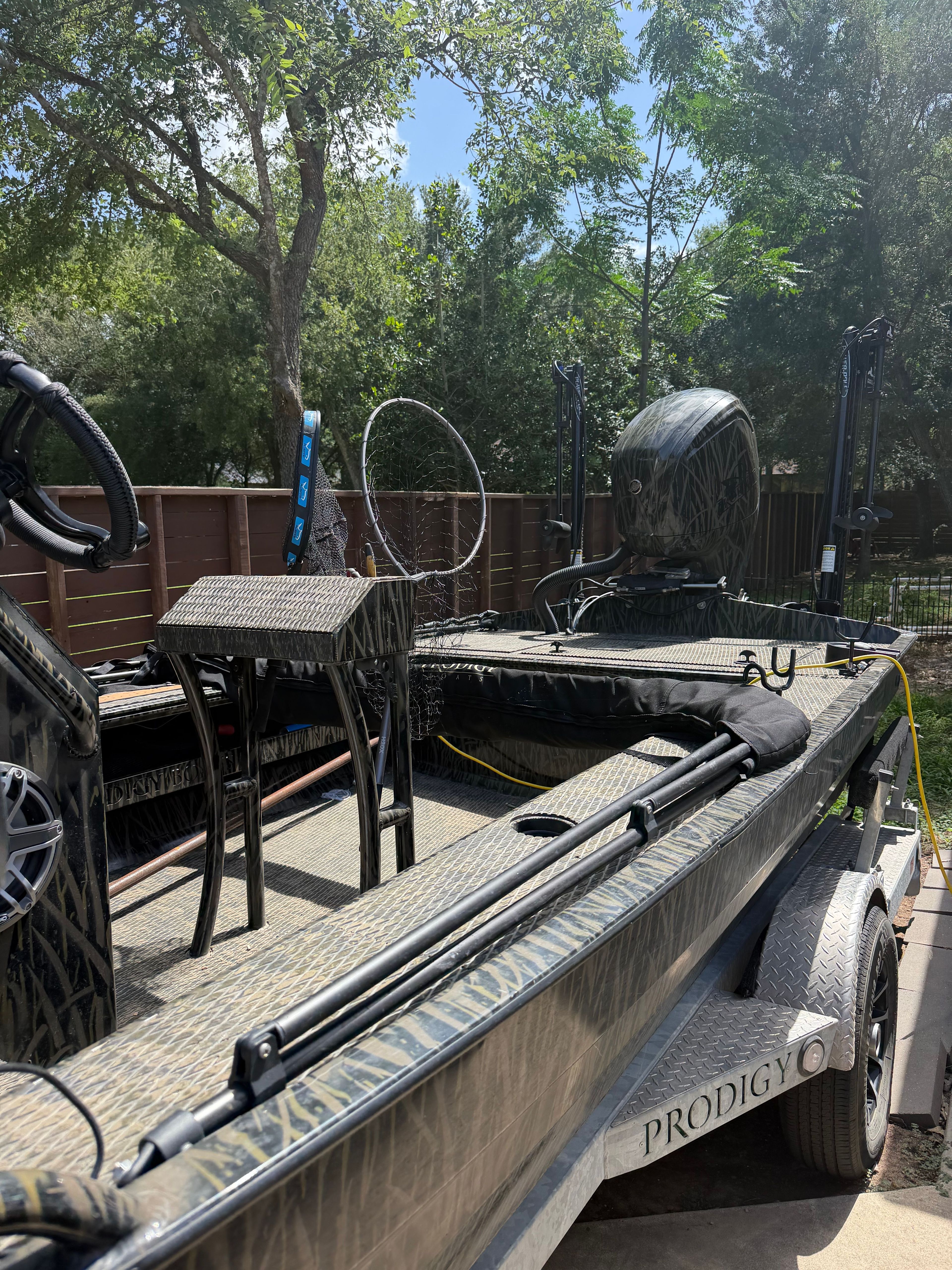A 2023 Prodigy 1860 boat on a trailer, surrounded by trees.
