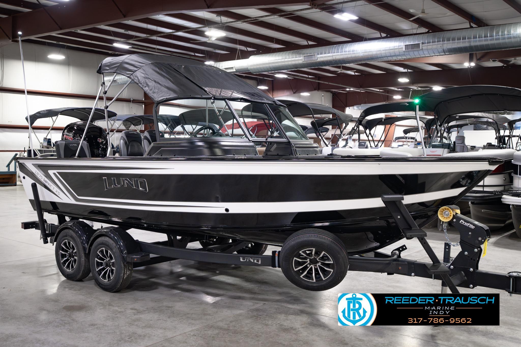 2026 Lund 1875 Impact XS SS boat in showroom, black and white design, on trailer.