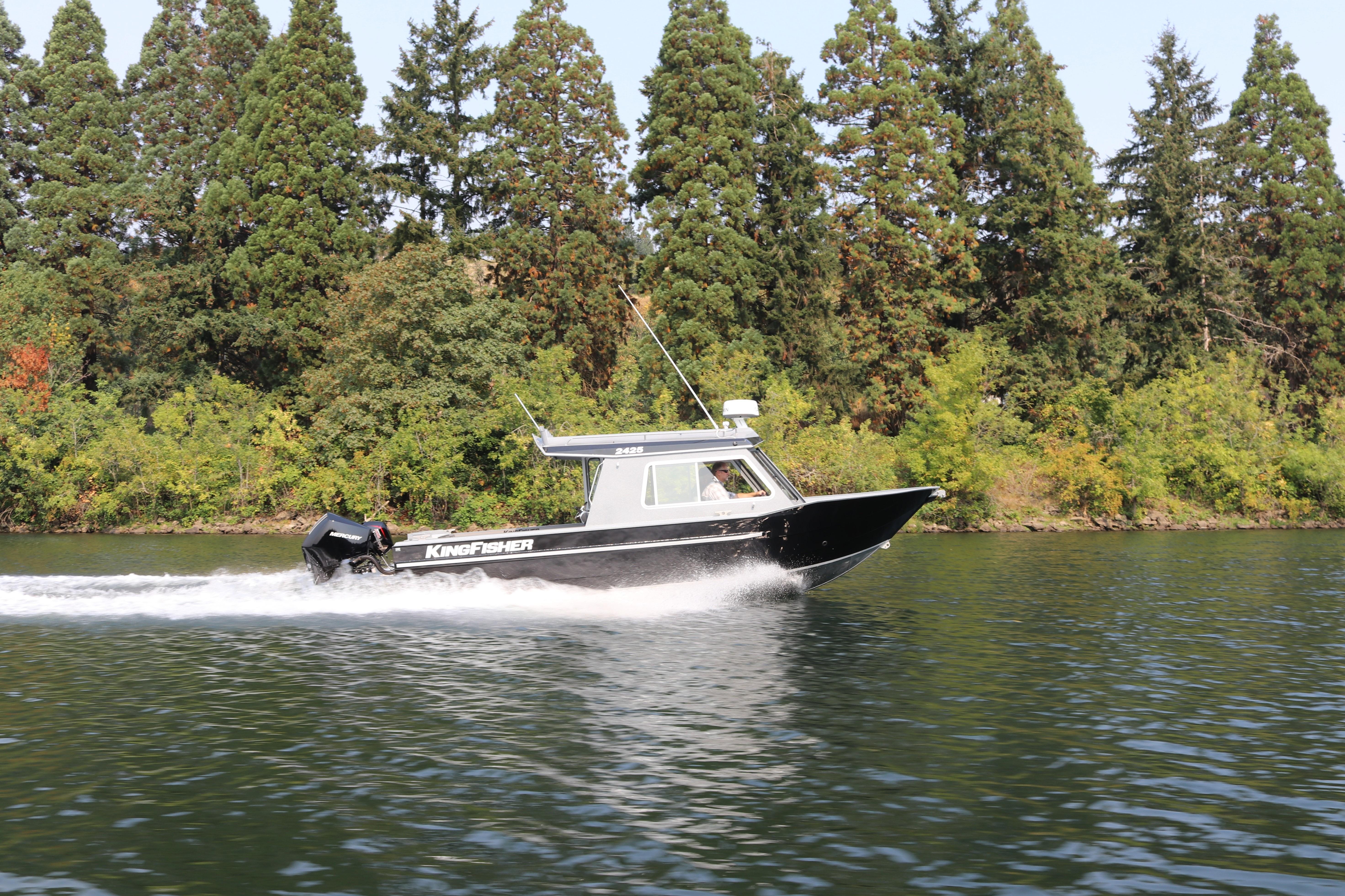 2026 KingFisher 2425 Escape HT boat cruising on a scenic lake with forest backdrop.