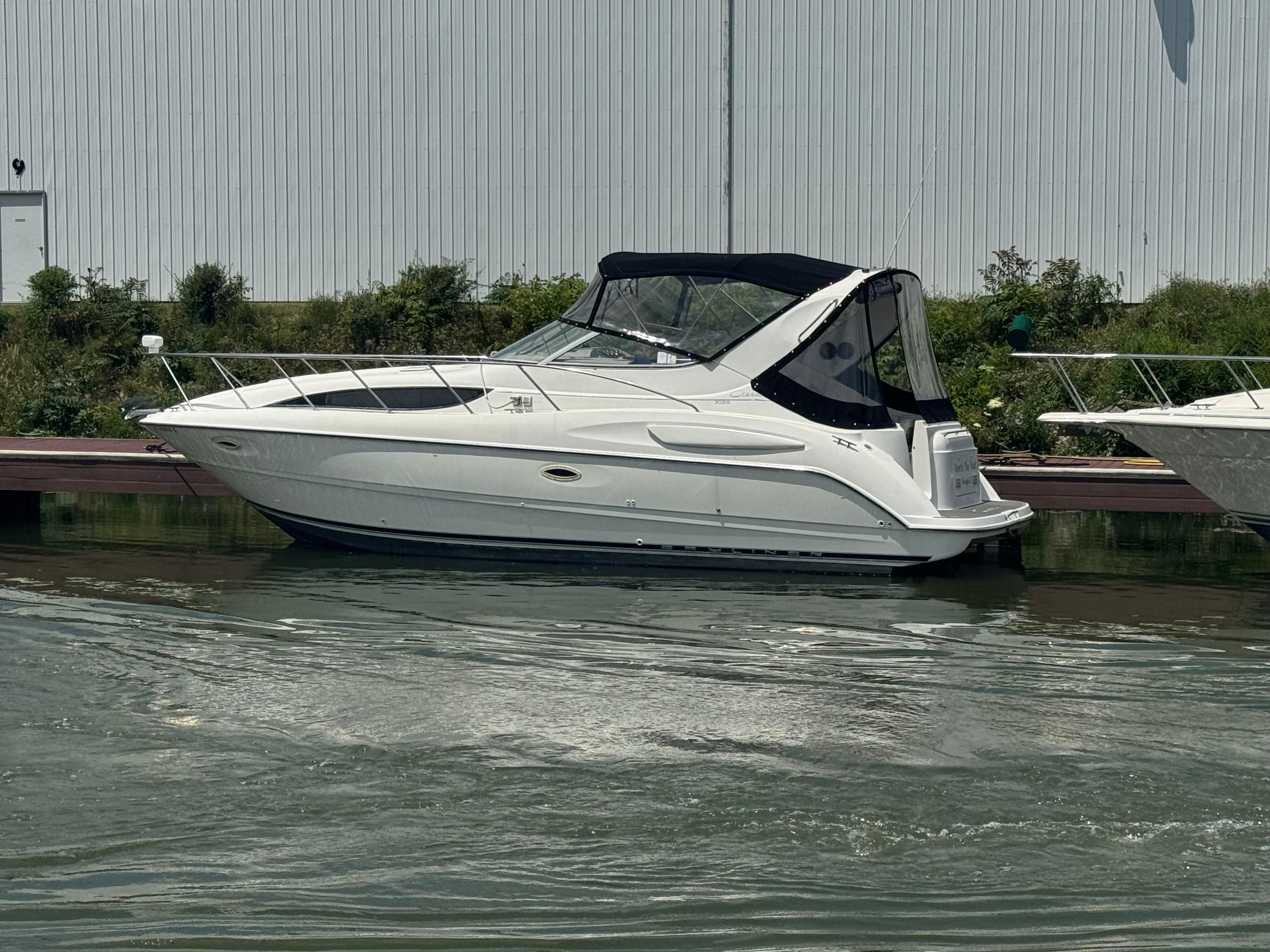 1999 Bayliner 3055 Ciera boat docked on calm water near a marina.