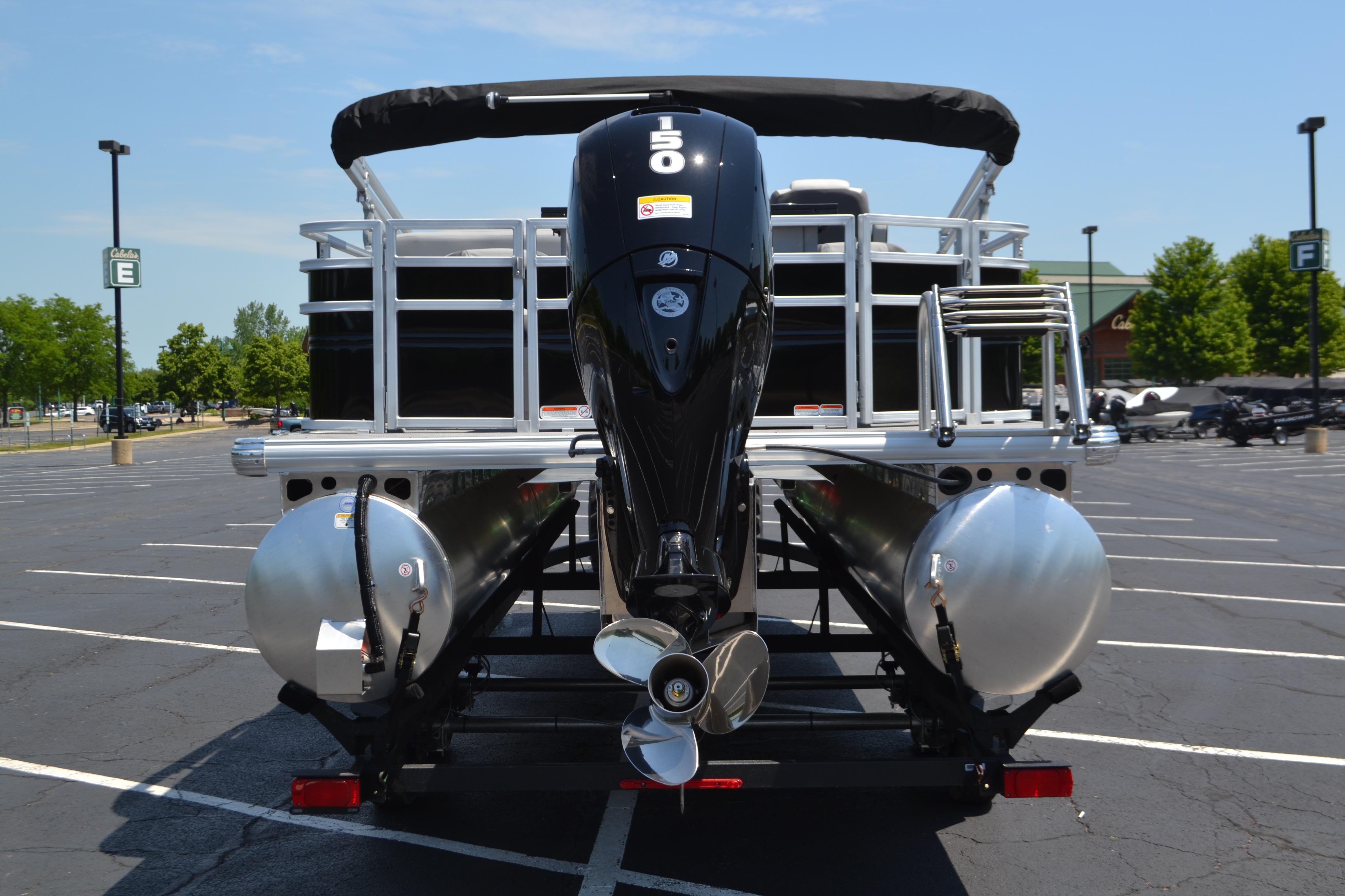 2026 Sun Tracker SportFish 22 DLX pontoon boat with powerful outboard motor in parking lot.