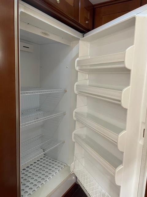 Empty refrigerator inside 1982 Cheoy Lee 66 LRC yacht, featuring wooden cabinetry.