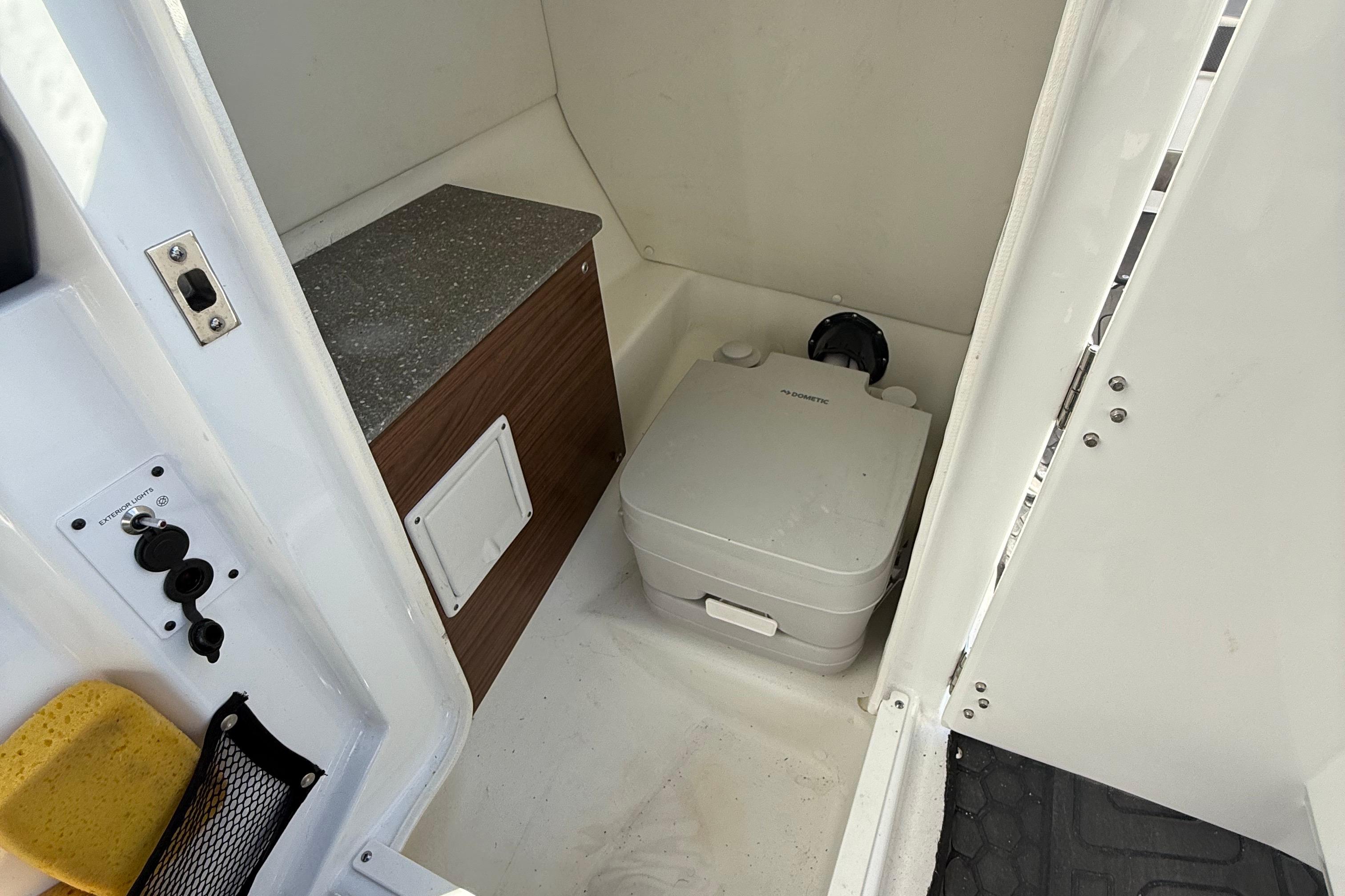 2021 Scarab 255 ID boat interior with compact marine toilet and storage area.