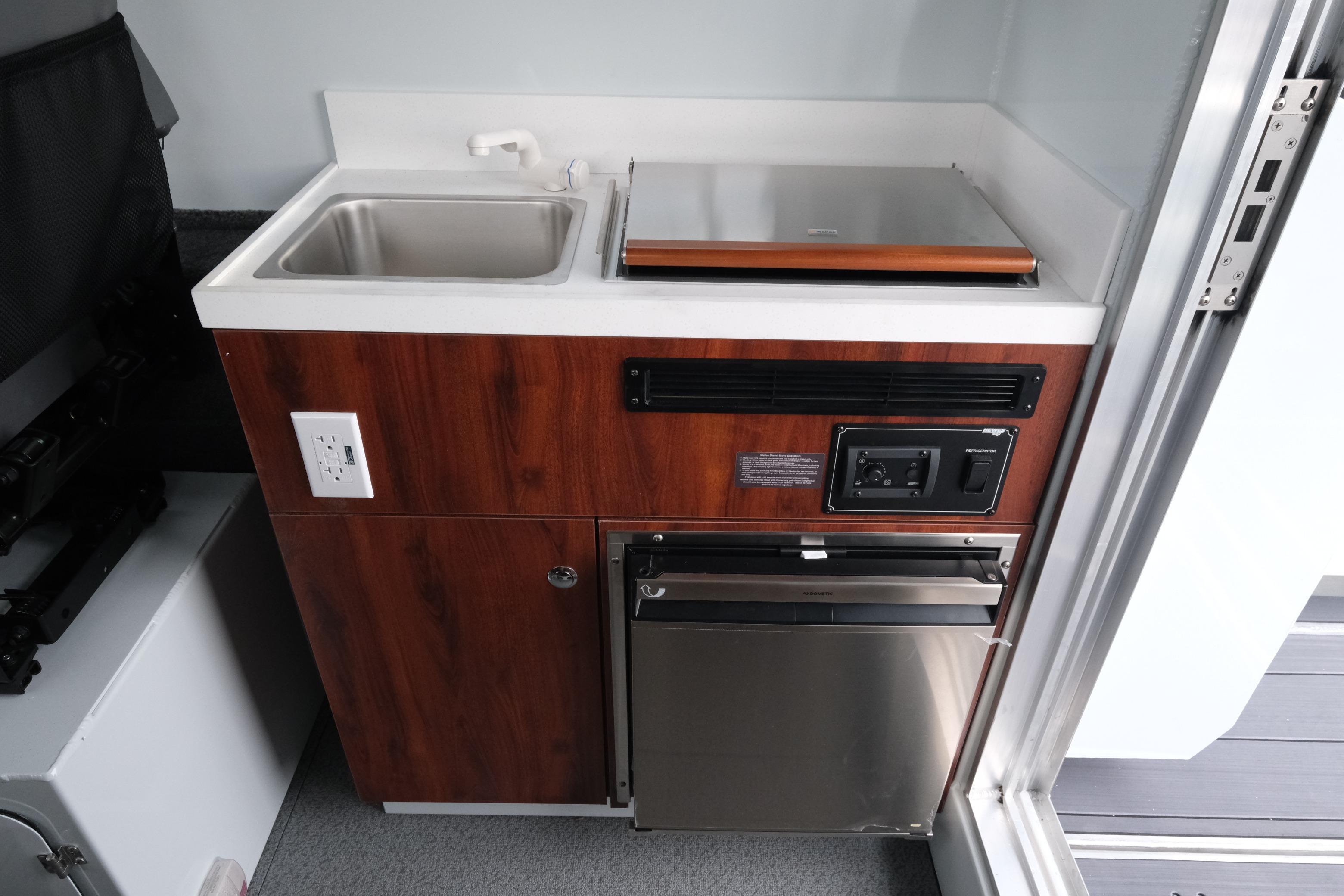 2026 Hewescraft 270 Pacific Explorer kitchenette with sink, stove, and storage.