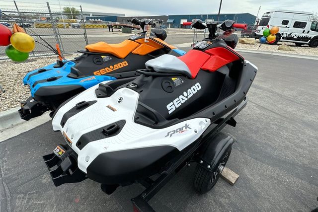 Two Sea-Doo jet skis, one red and white, the other blue and orange, on a trailer.