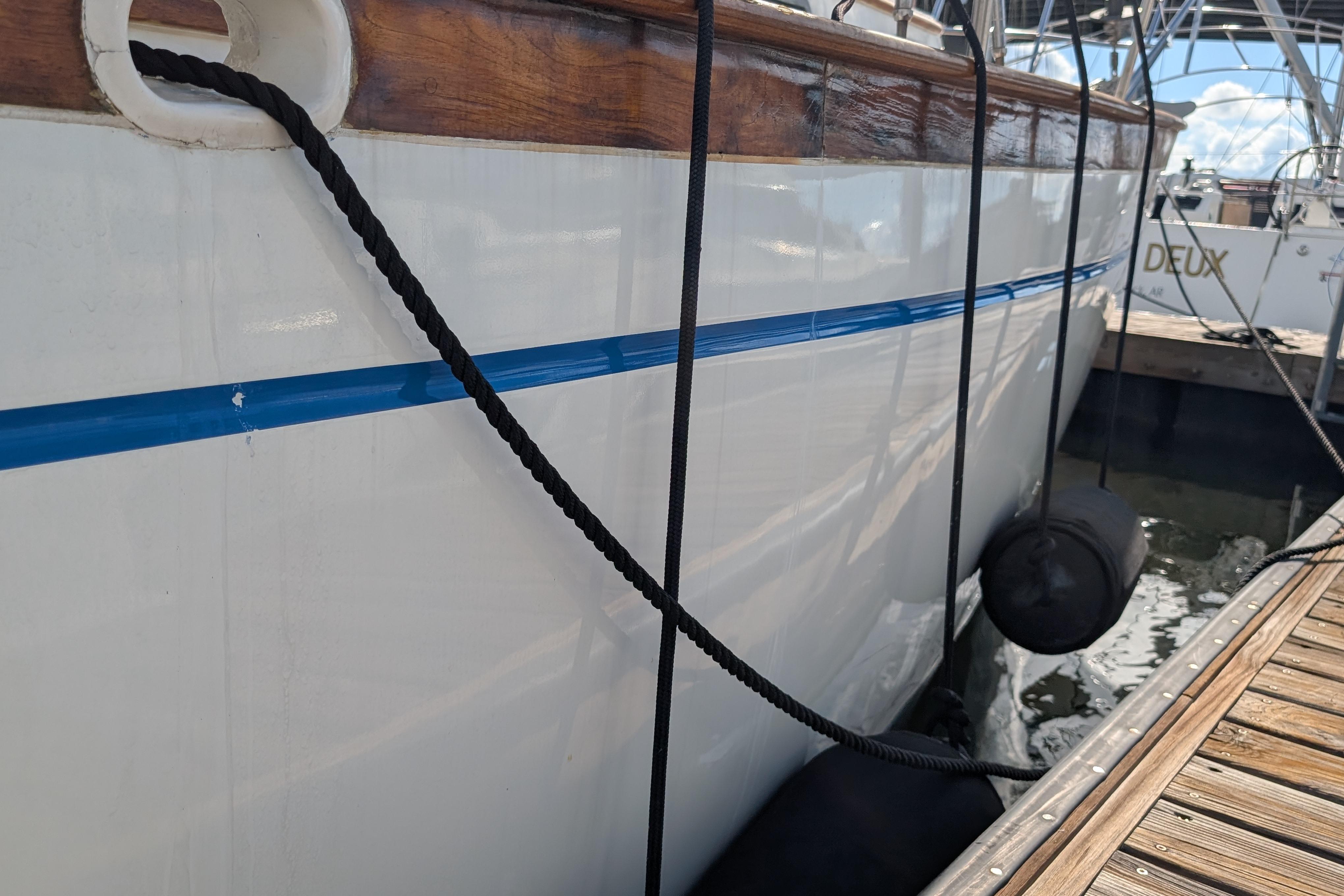 Side view of a 1983 Robert Perry 41 yacht docked with fenders and ropes.