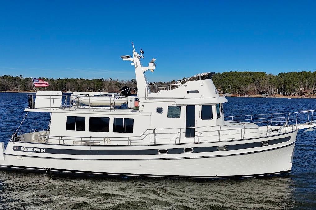 2007 Nordic Tug 54 cruising on a lake under clear blue skies.