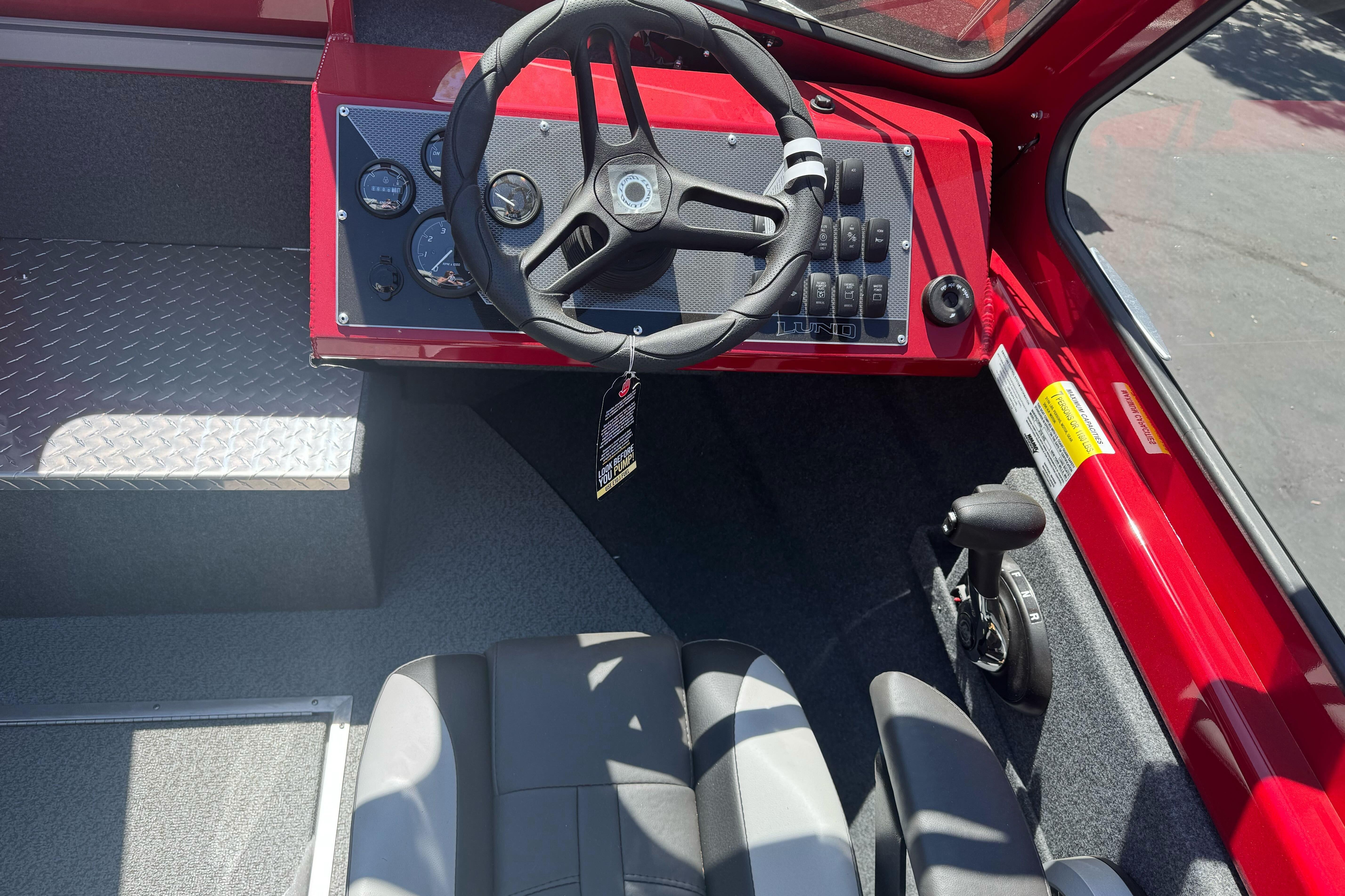 Interior of 2026 Lund 210 Heavy Gauge boat with steering wheel and control panel.