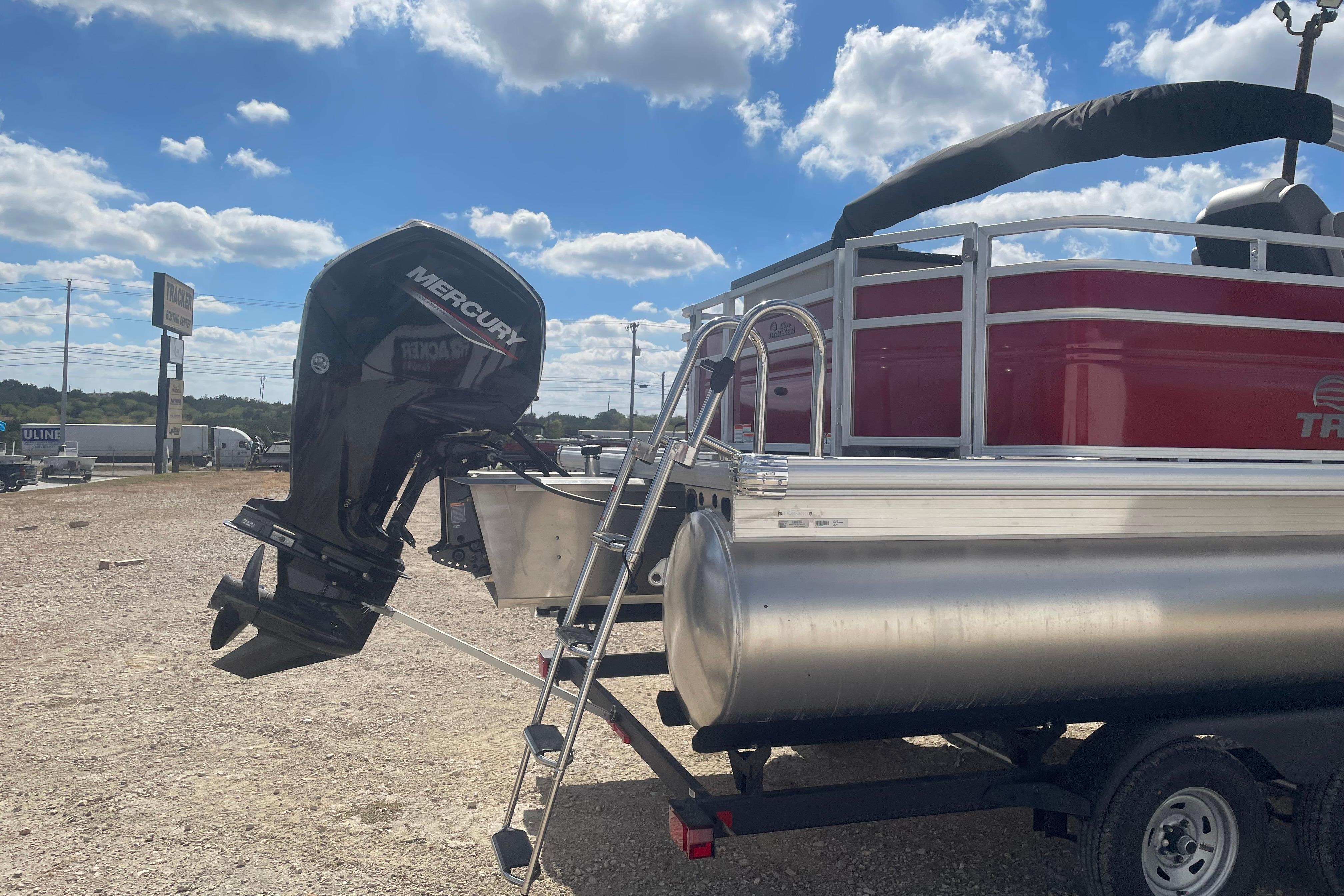 2026 Sun Tracker Fishin' Barge 22 DLX with Mercury outboard motor, parked outdoors.