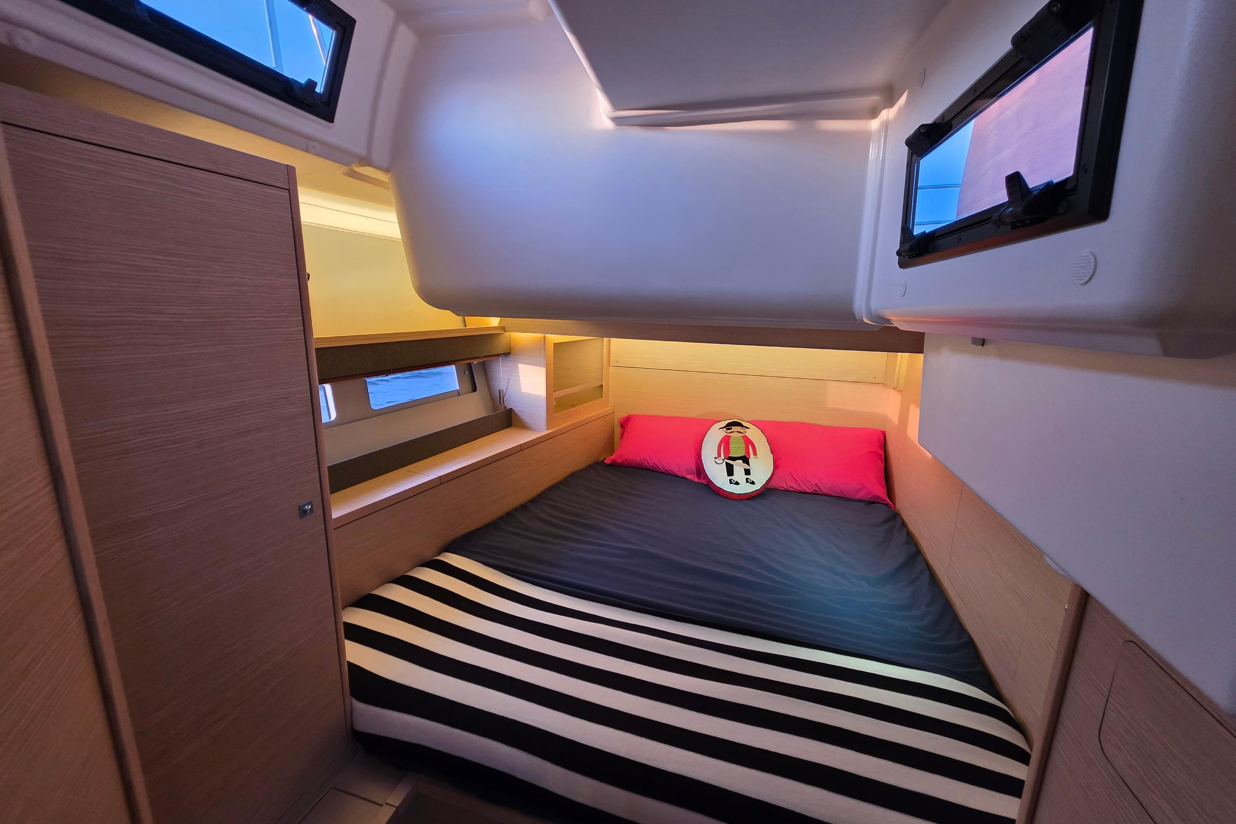 2024 Dufour 530 yacht cabin with cozy bed, striped blanket, and nautical decor.