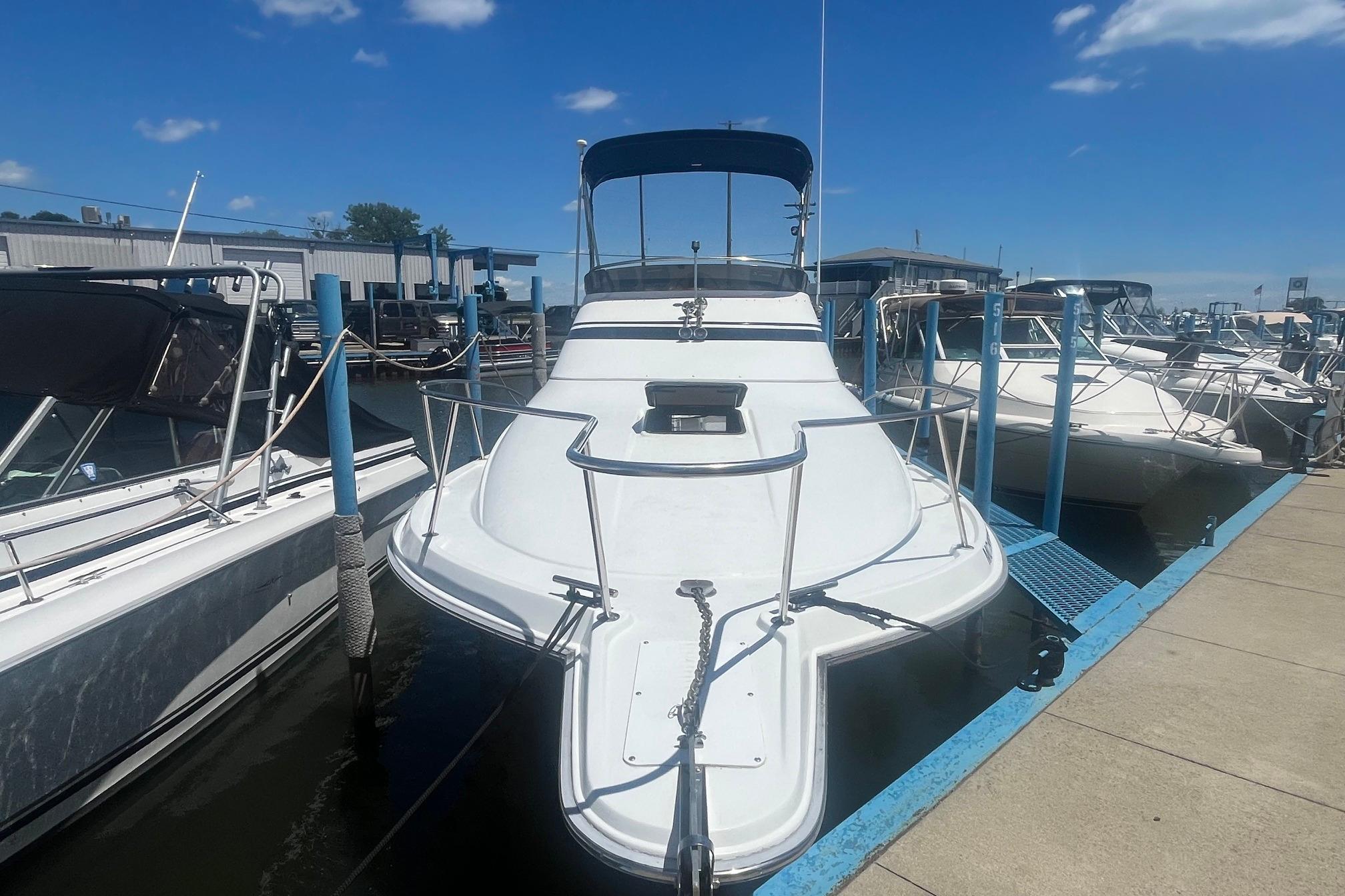 1988 Seafox 29 Flybridge boat docked at marina under clear blue sky.