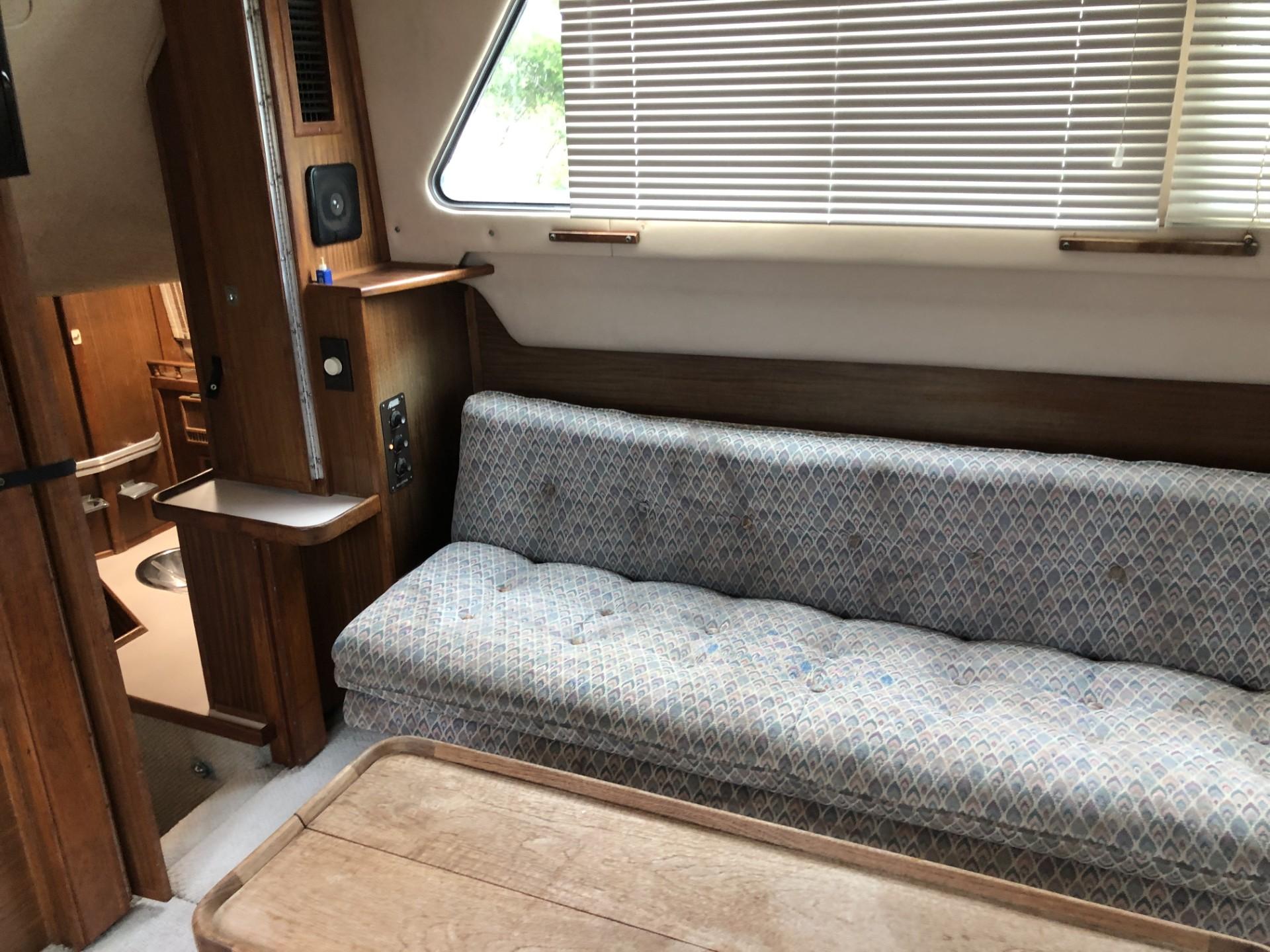 1987 Sea Ray 360 Aft Cabin interior with sofa, wooden table, and window blinds.