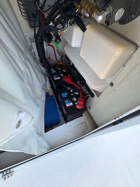 Batteries and wiring inside a boat, surrounded by white coverings.