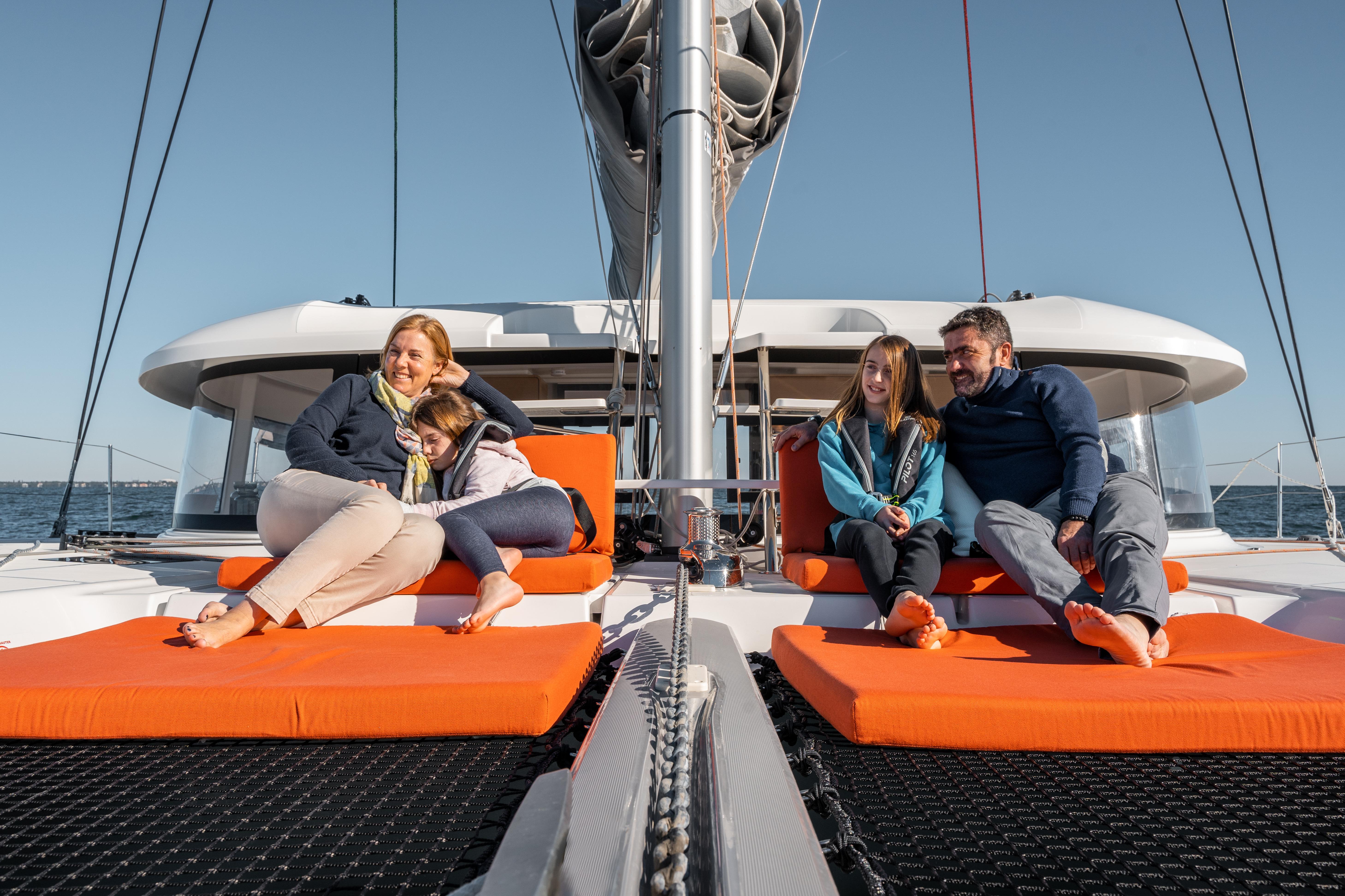 Family relaxing on 2026 Excess 14 catamaran, enjoying a sunny day at sea.