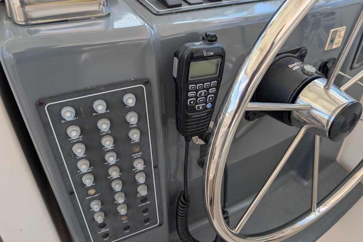 Control panel of a 2000 Pursuit 3400 Express boat with steering wheel and radio.